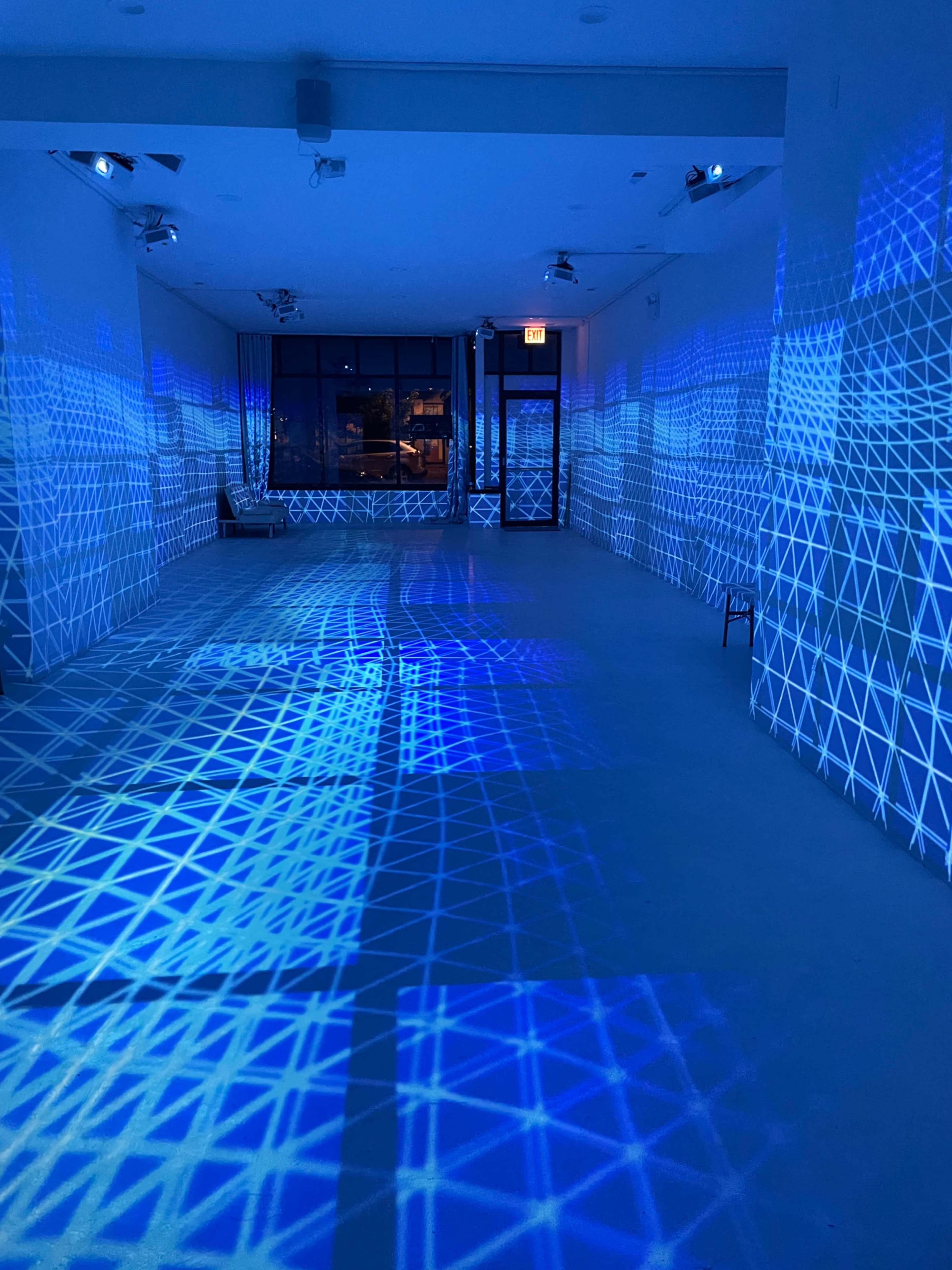 An empty room with blue geometric light patterns projected onto the walls and floor.
