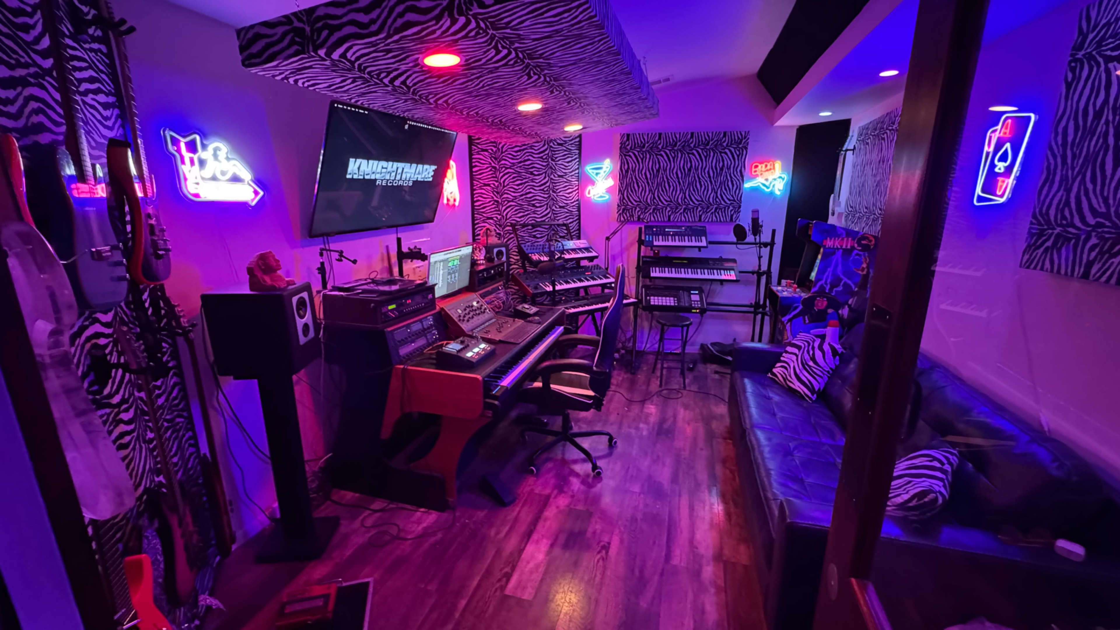 The image depicts a vibrant music studio decorated with zebra-striped walls, neon lights, and various musical equipment arranged around a central workstation.