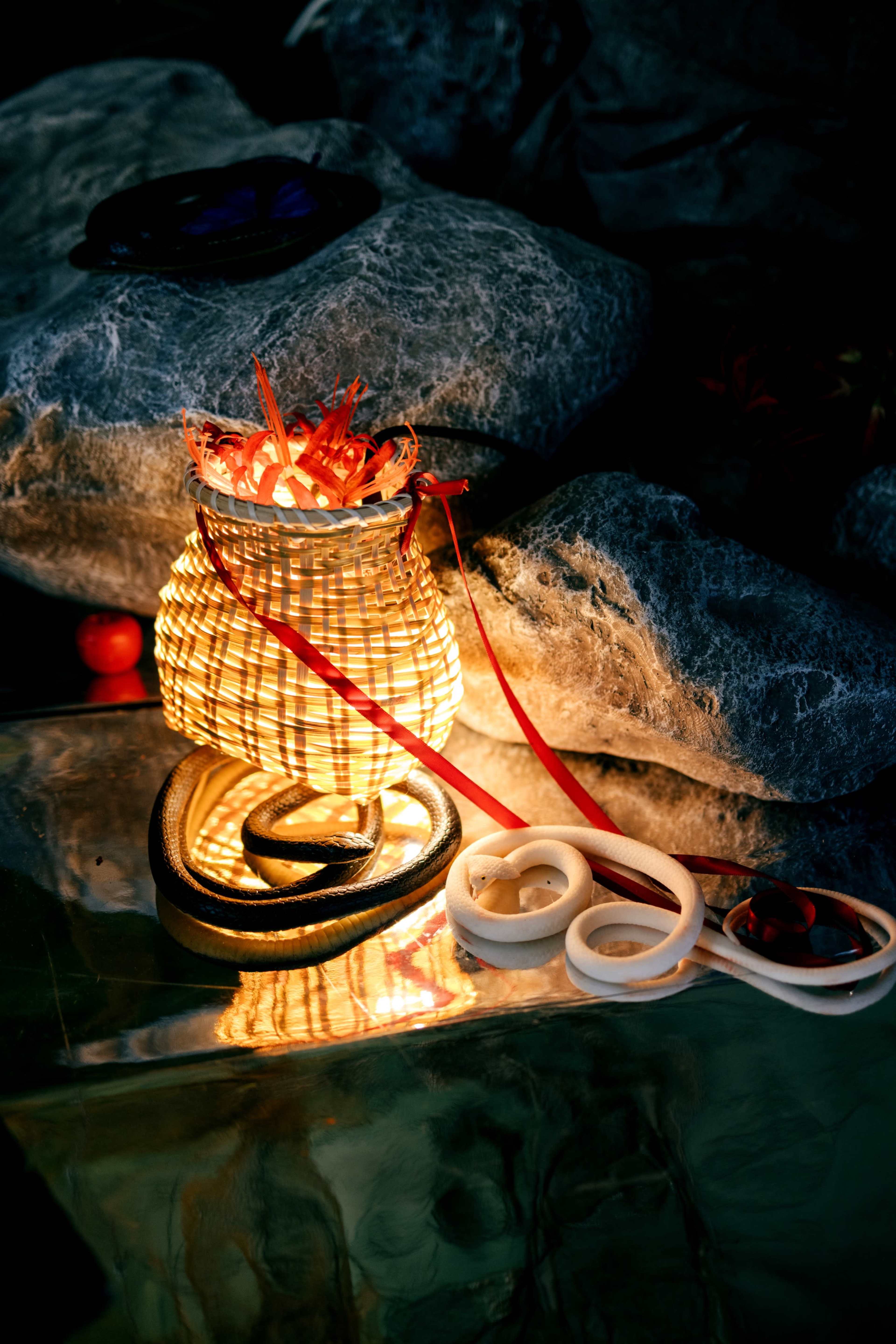 A woven basket emits light and is surrounded by rocks and various decorative items.