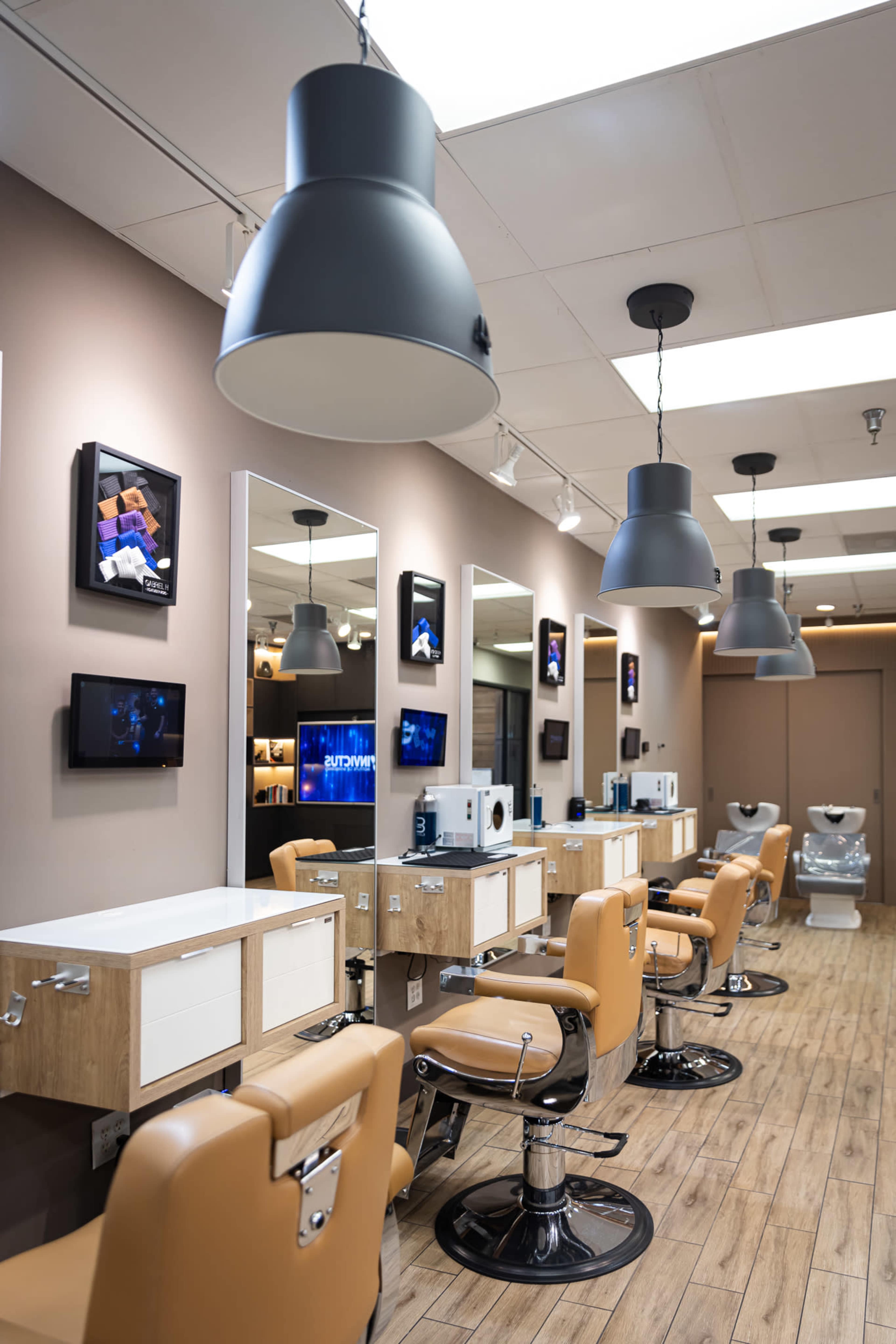 The image shows a modern hair salon with several styling stations, each equipped with mirrors and adjustable salon chairs, under industrial-style pendant lights.