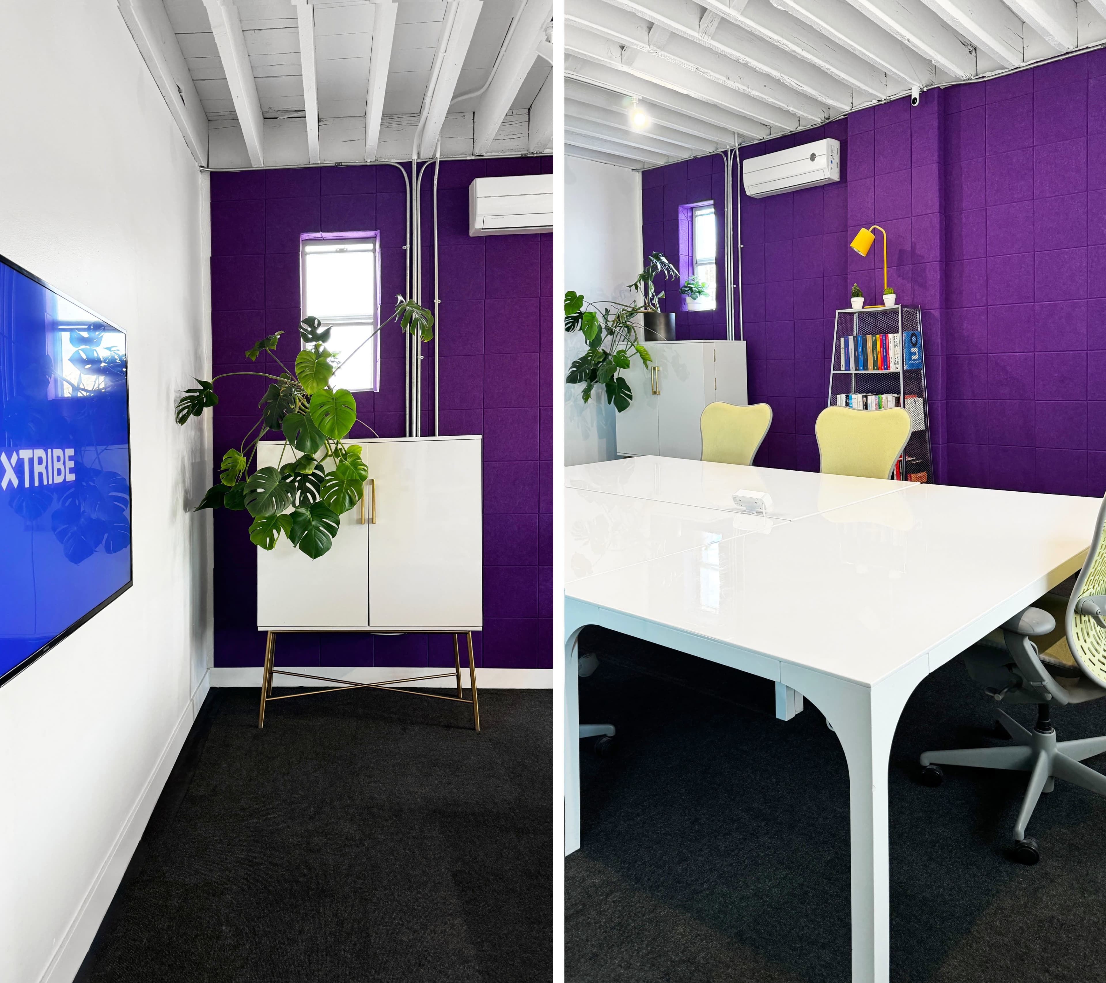 A modern office space featuring a purple accent wall, a white cabinet with a plant, and a large white table surrounded by yellow chairs.