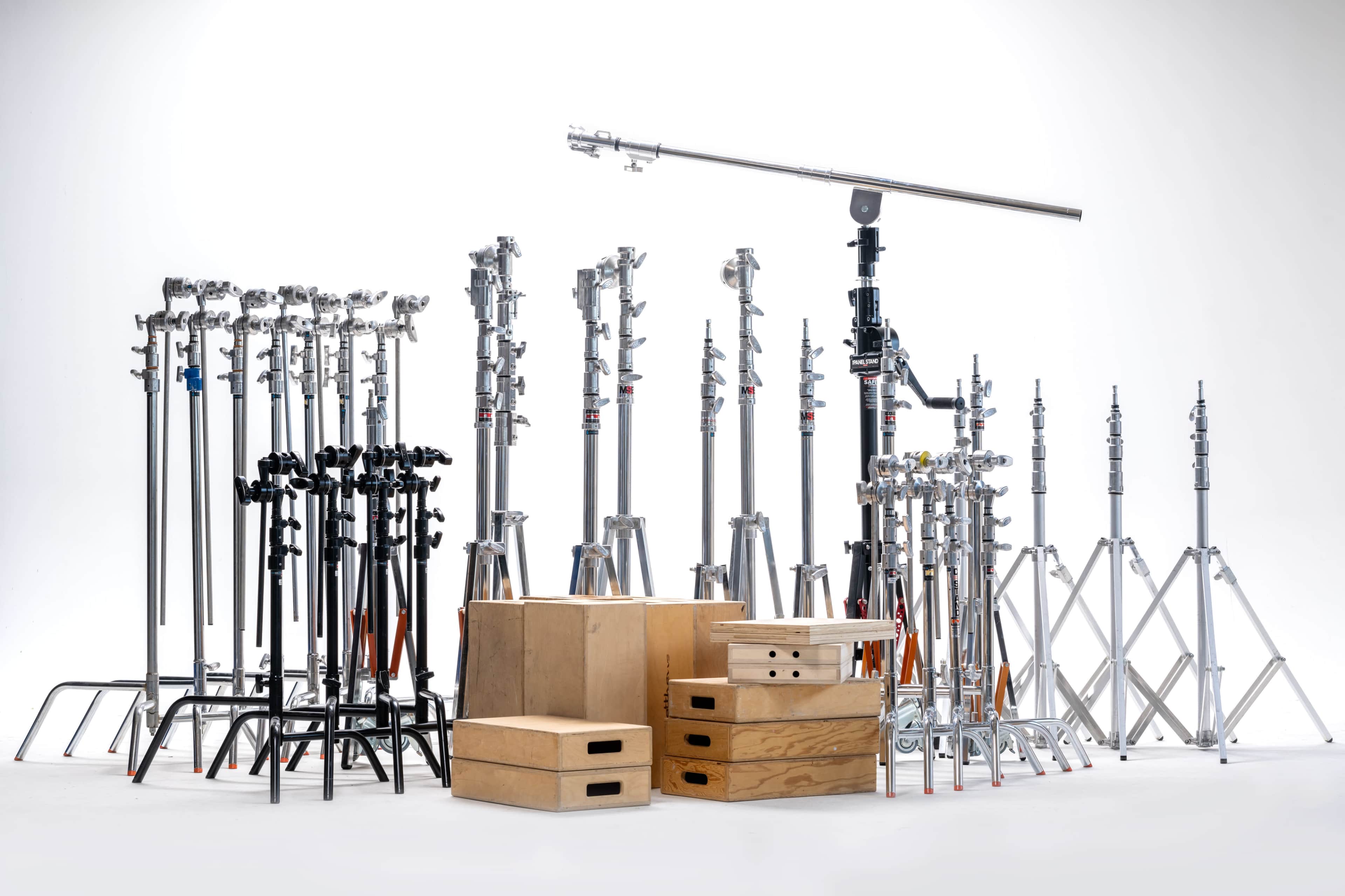 A collection of photography light stands and equipment arranged alongside wooden boxes.