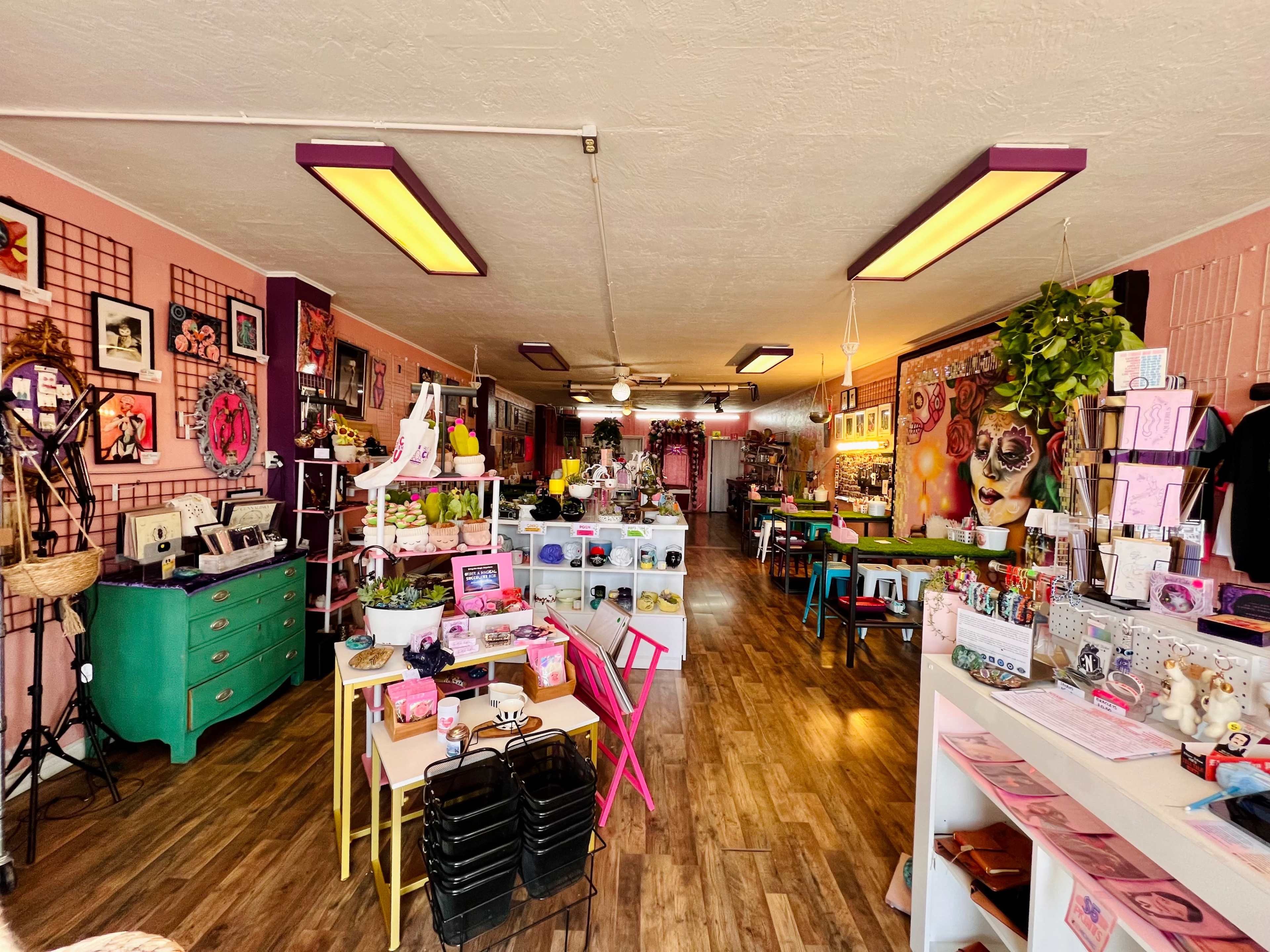 A colorful boutique filled with various decorative items, plants, and art displayed on the walls and shelves.