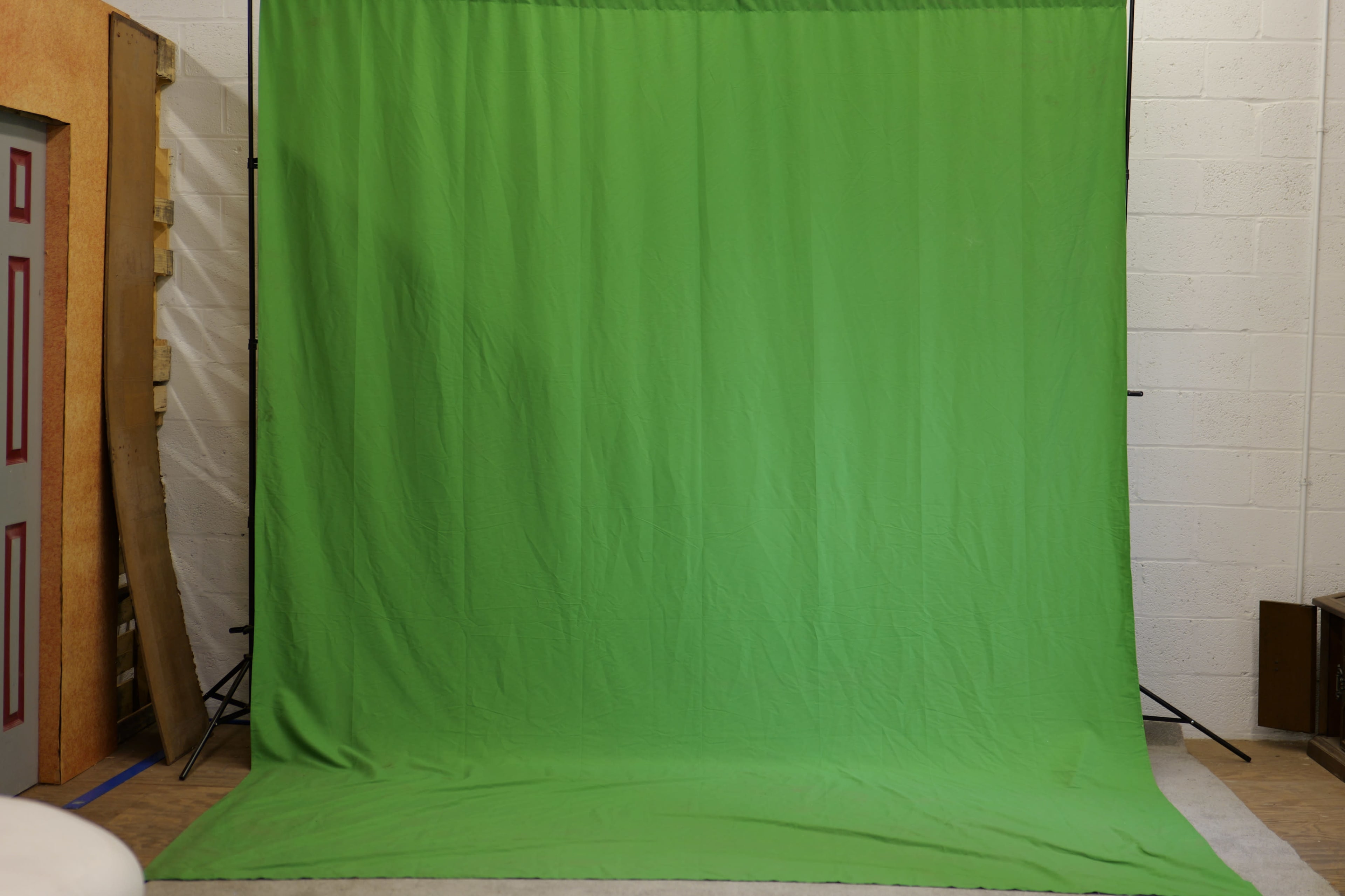 A large green backdrop set up in a studio environment.