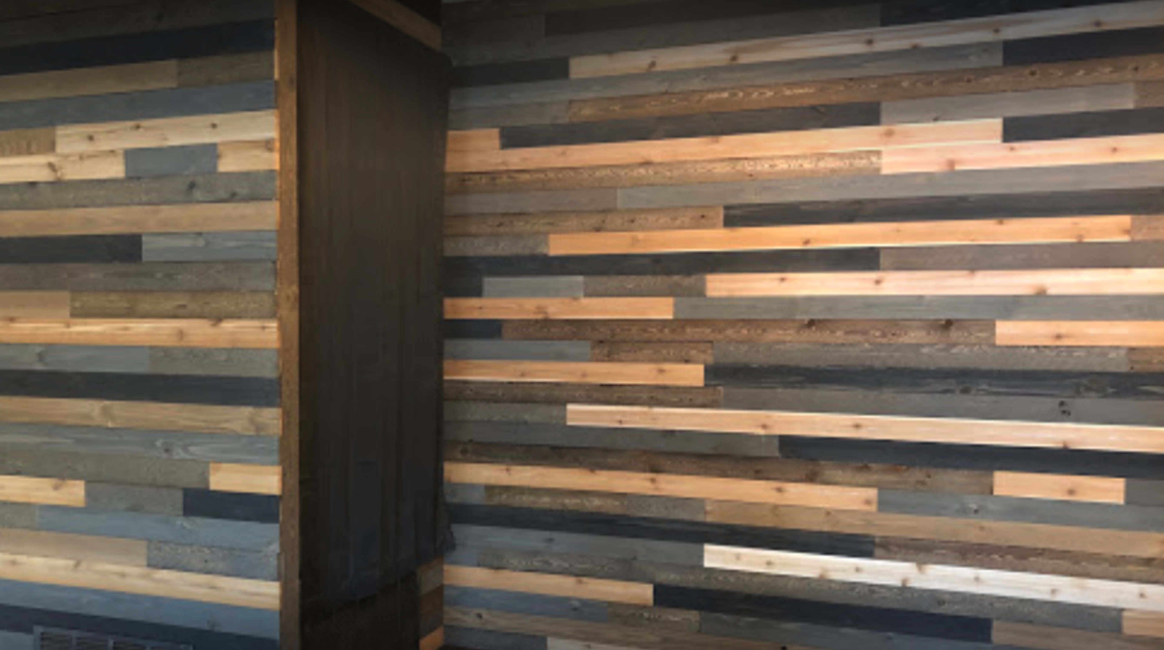 A wall made of wooden planks in various shades, arranged in a horizontal pattern.