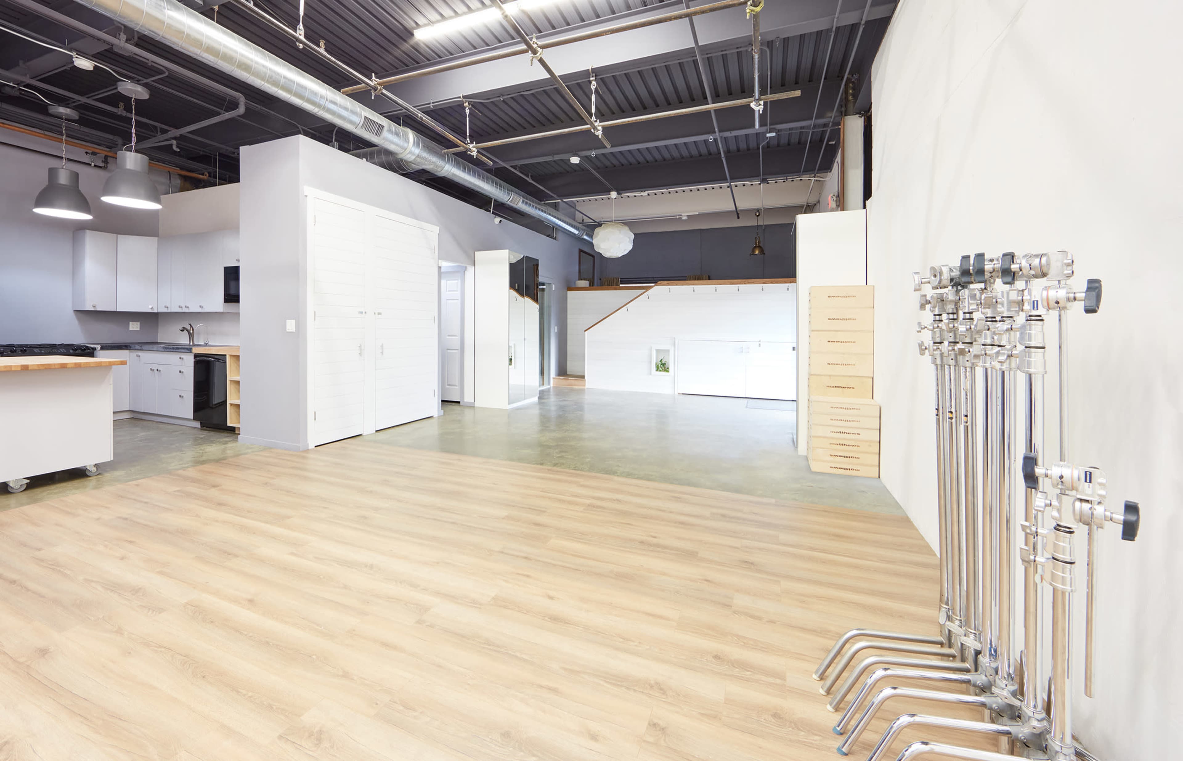 A spacious, modern interior with polished concrete floors, a kitchen area on the left, and a row of pipes along the right wall.