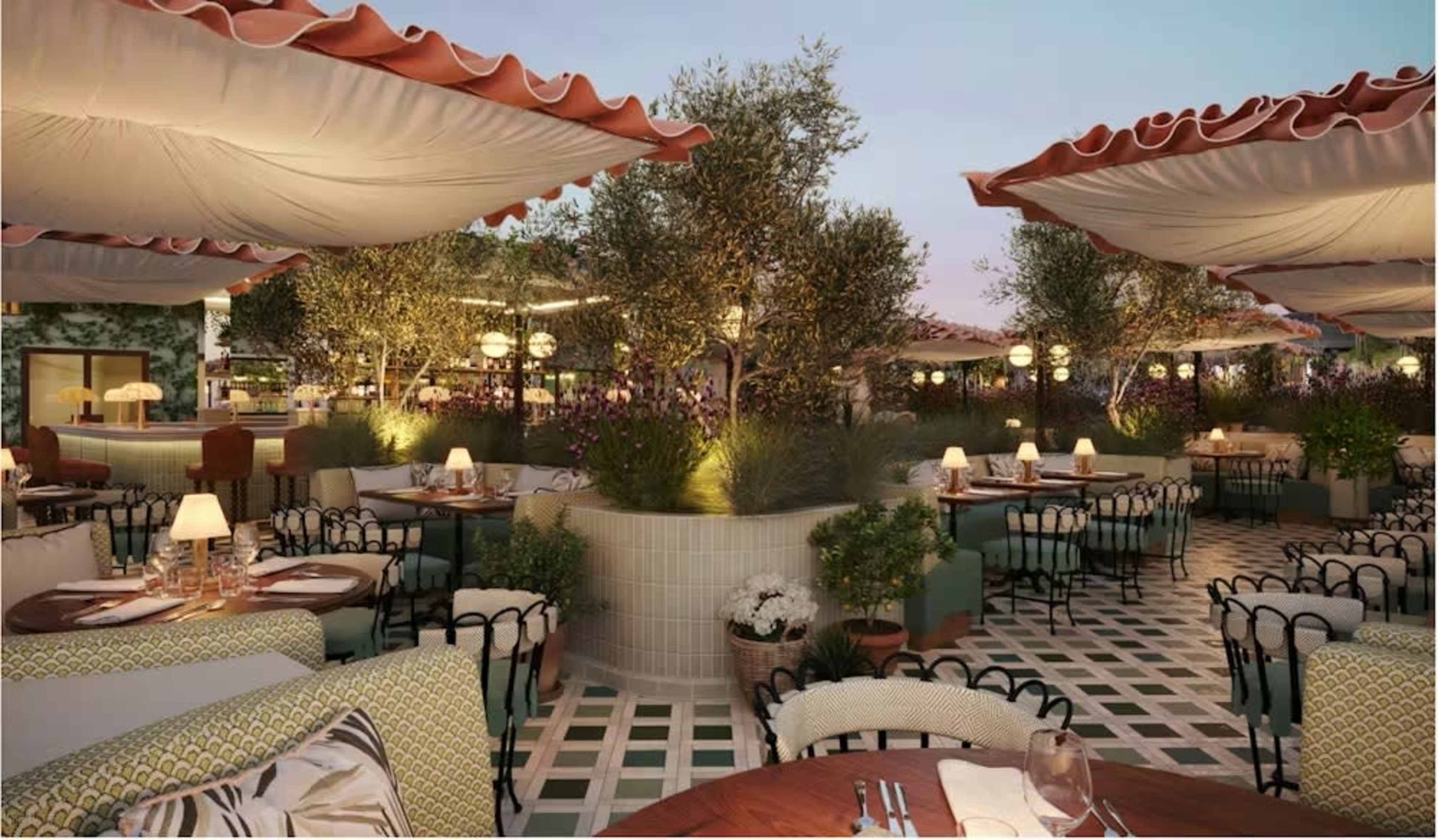 The image shows an outdoor dining area with tables and chairs underneath large fabric canopies, surrounded by potted plants and trees at dusk.