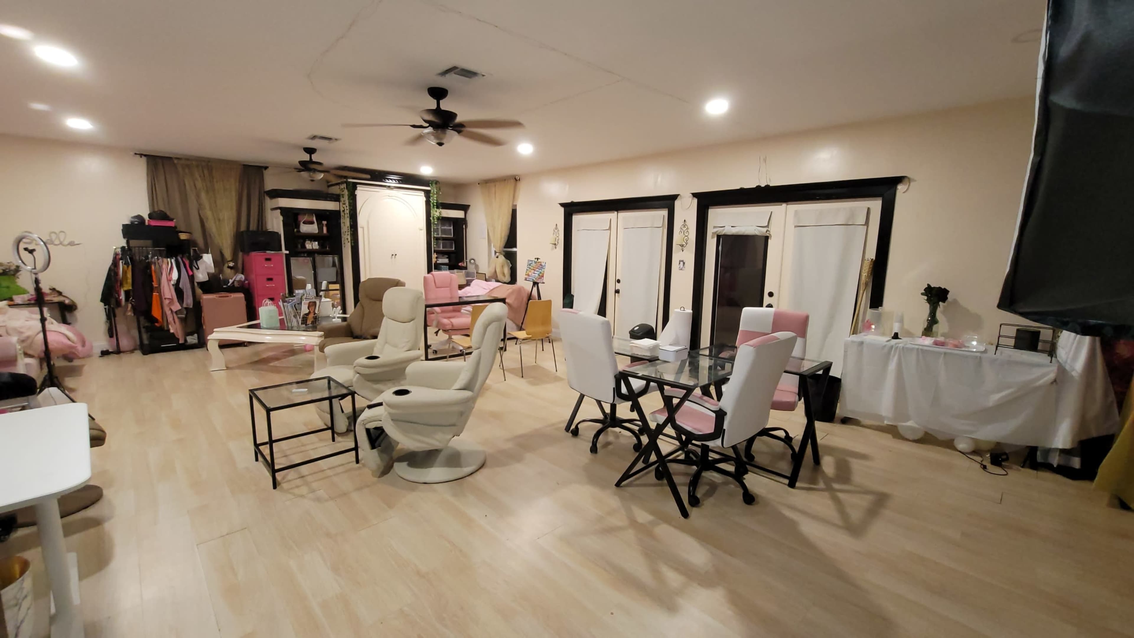 The image shows a spacious room furnished with several chairs, a dining table, and various storage units along the walls.