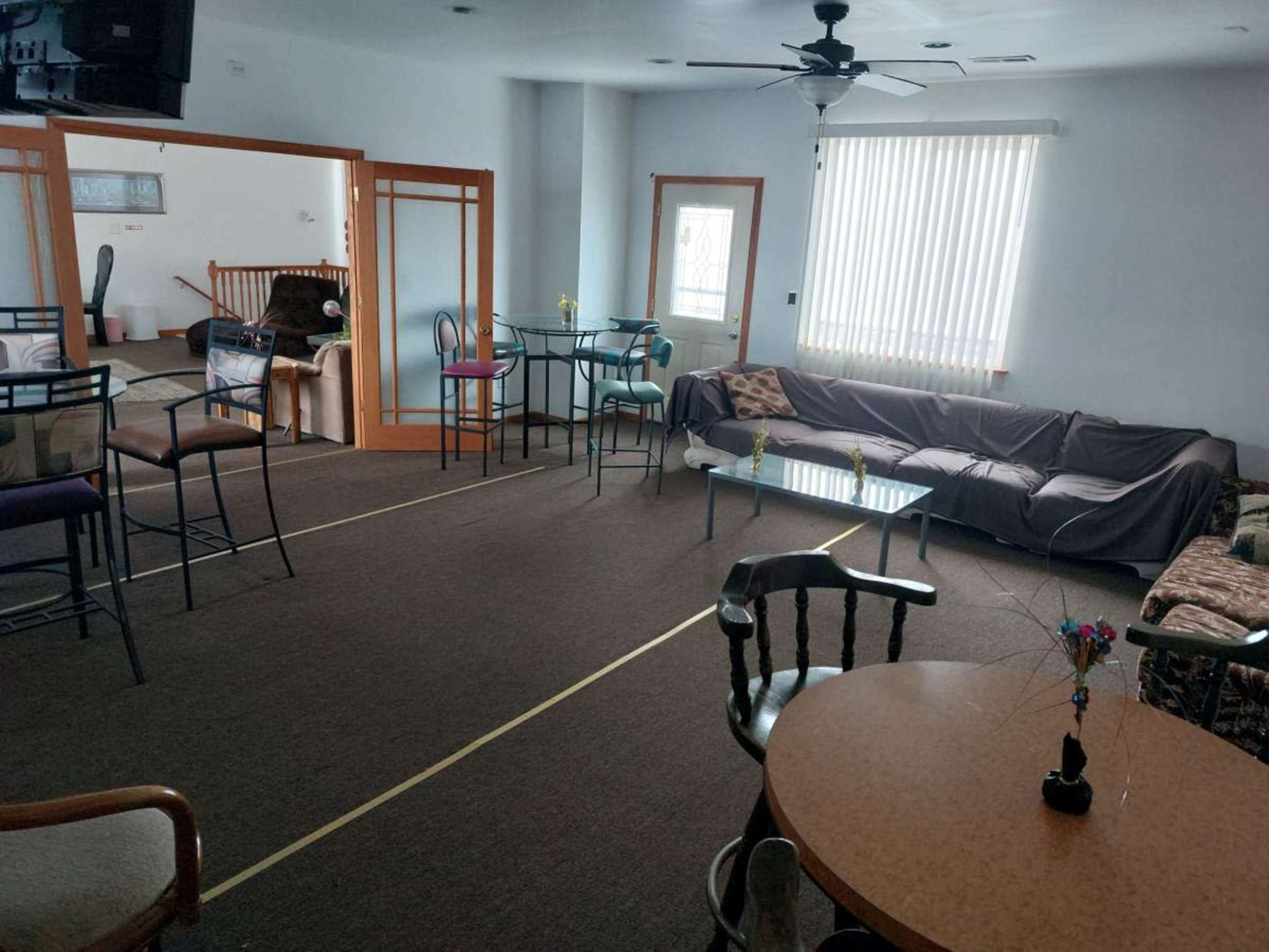 A spacious room furnished with tables, chairs, a couch, and a few decorative items.