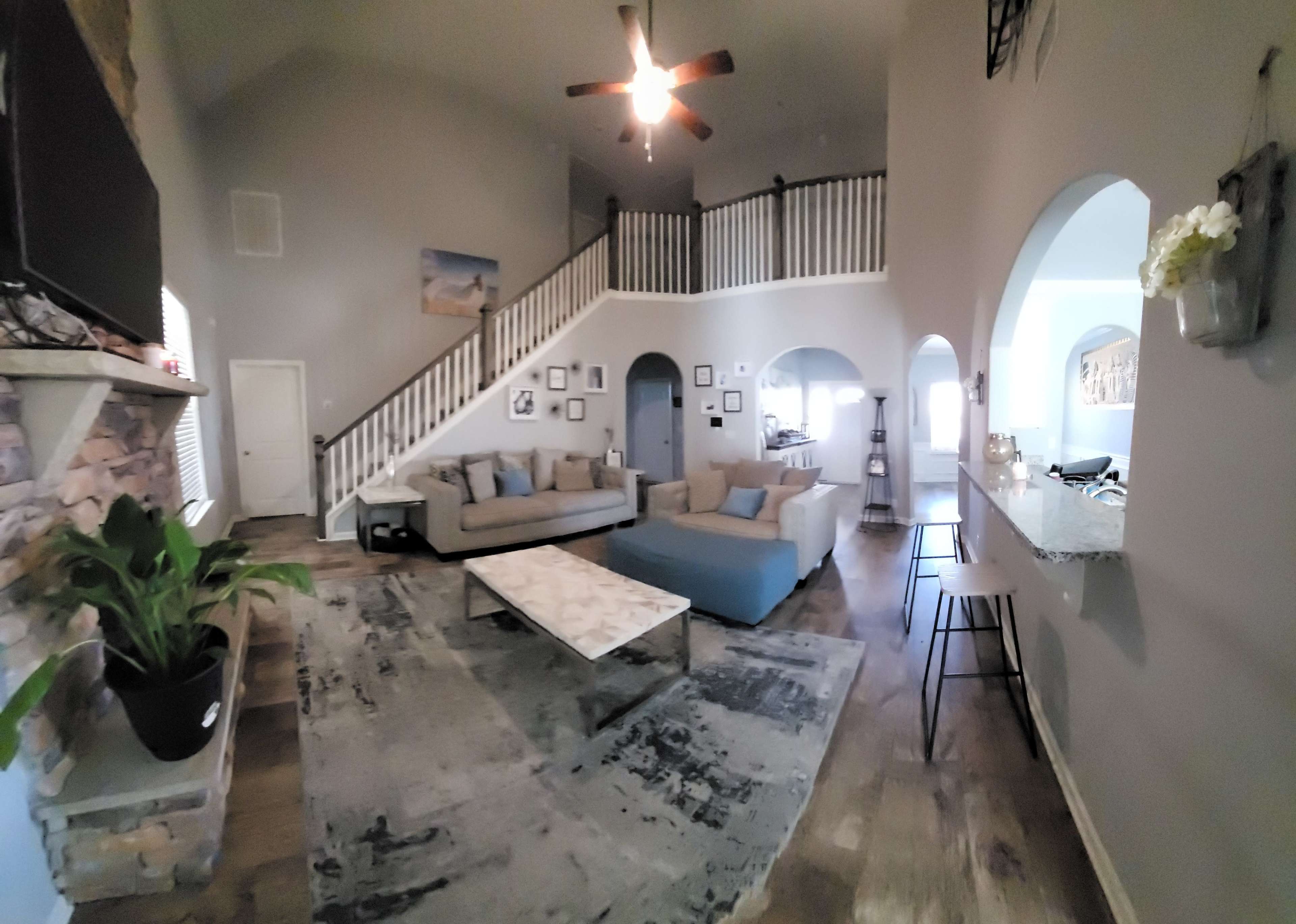 A spacious living room with a large sectional sofa, a coffee table, and a staircase leading to a second floor.