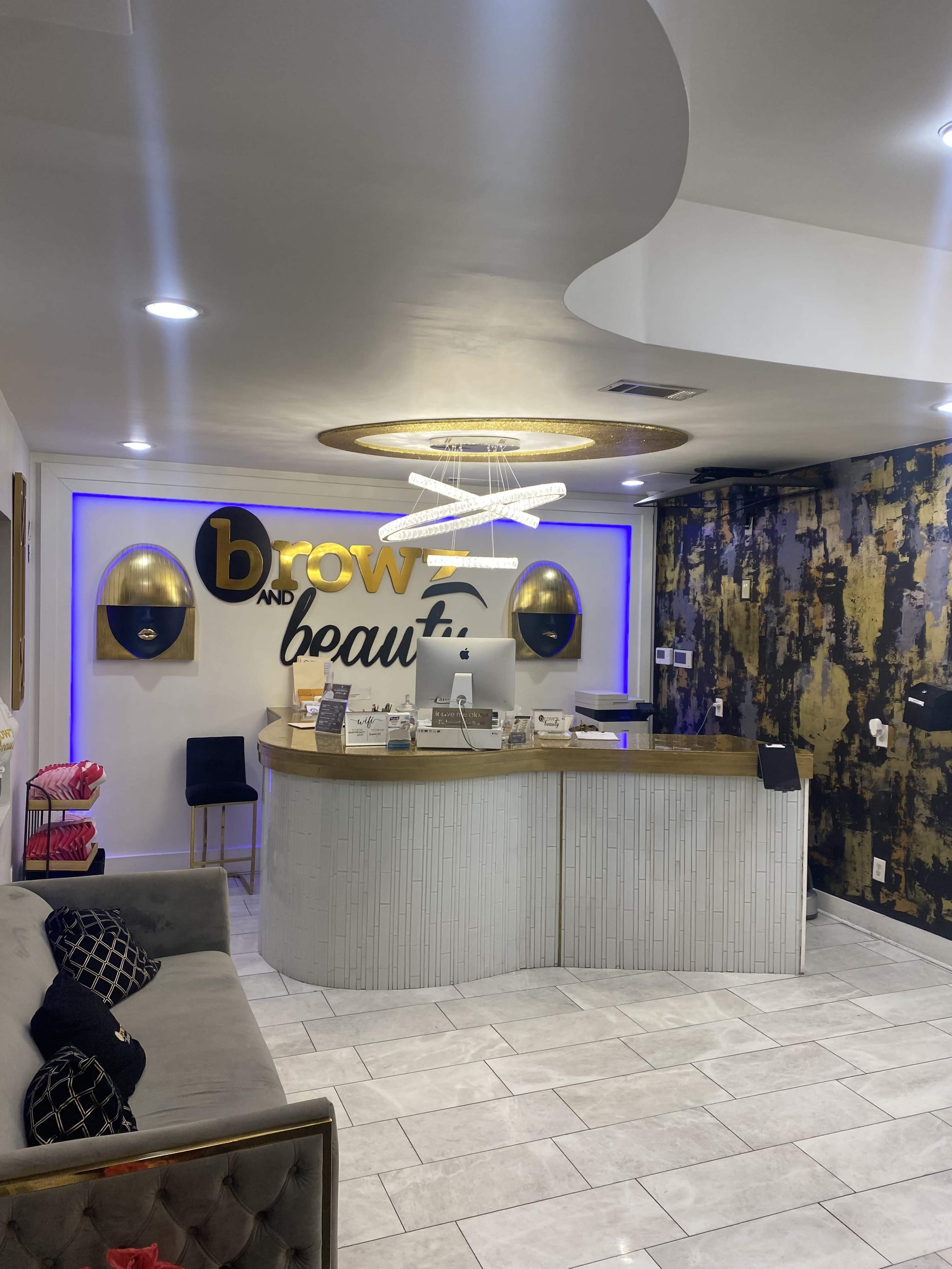 A modern beauty salon reception area with a gold and blue color scheme, featuring a curved front desk and stylish wall decor.