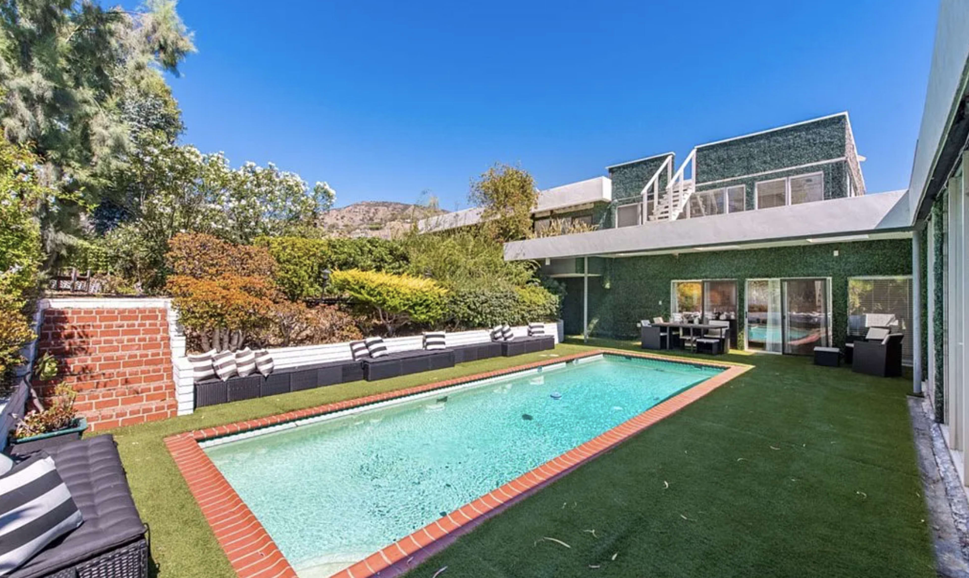 A modern house with a swimming pool surrounded by landscaped greenery and outdoor seating.