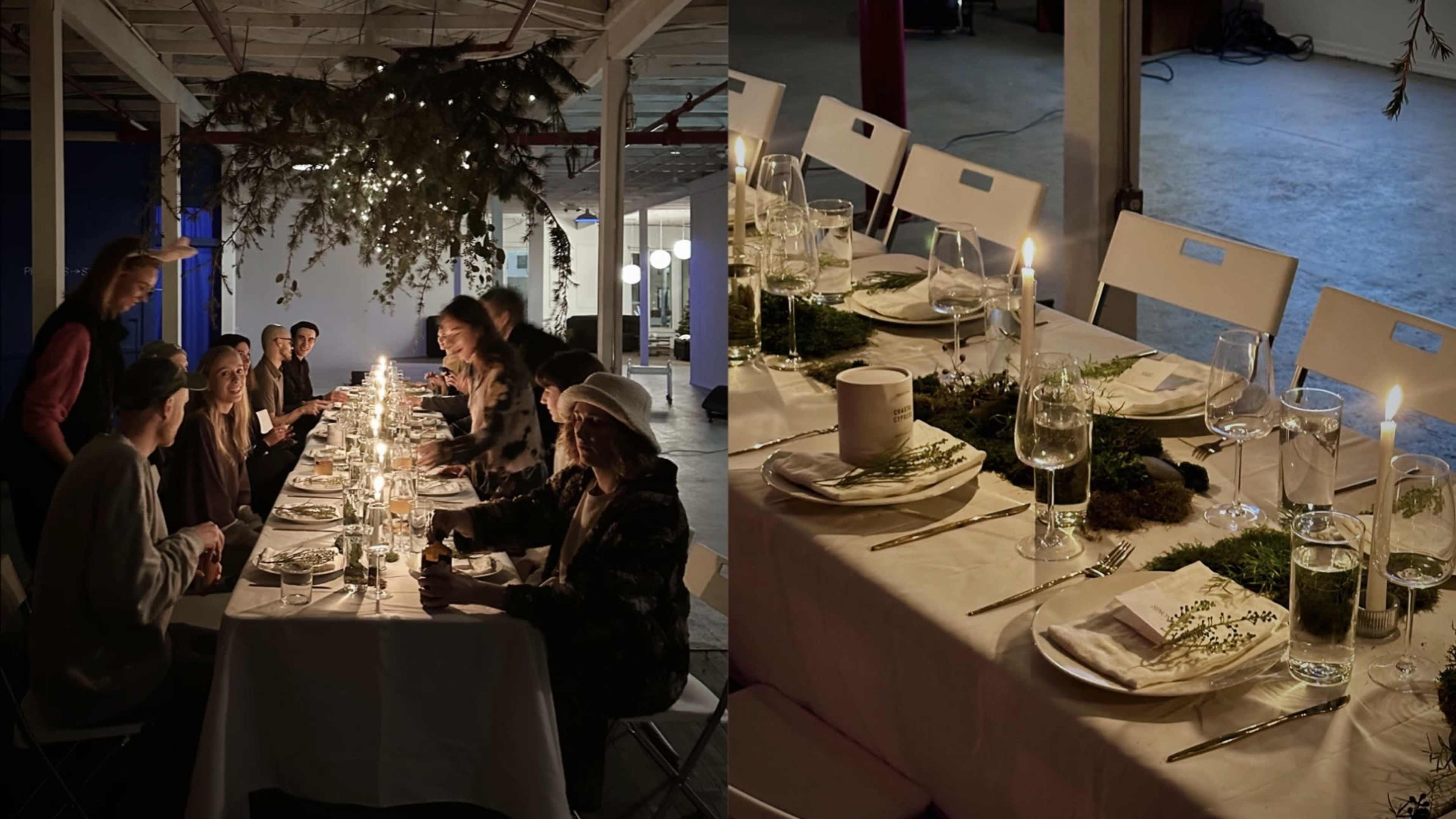 A long table is set with candles and greenery, surrounded by people dining in a decorated industrial space.