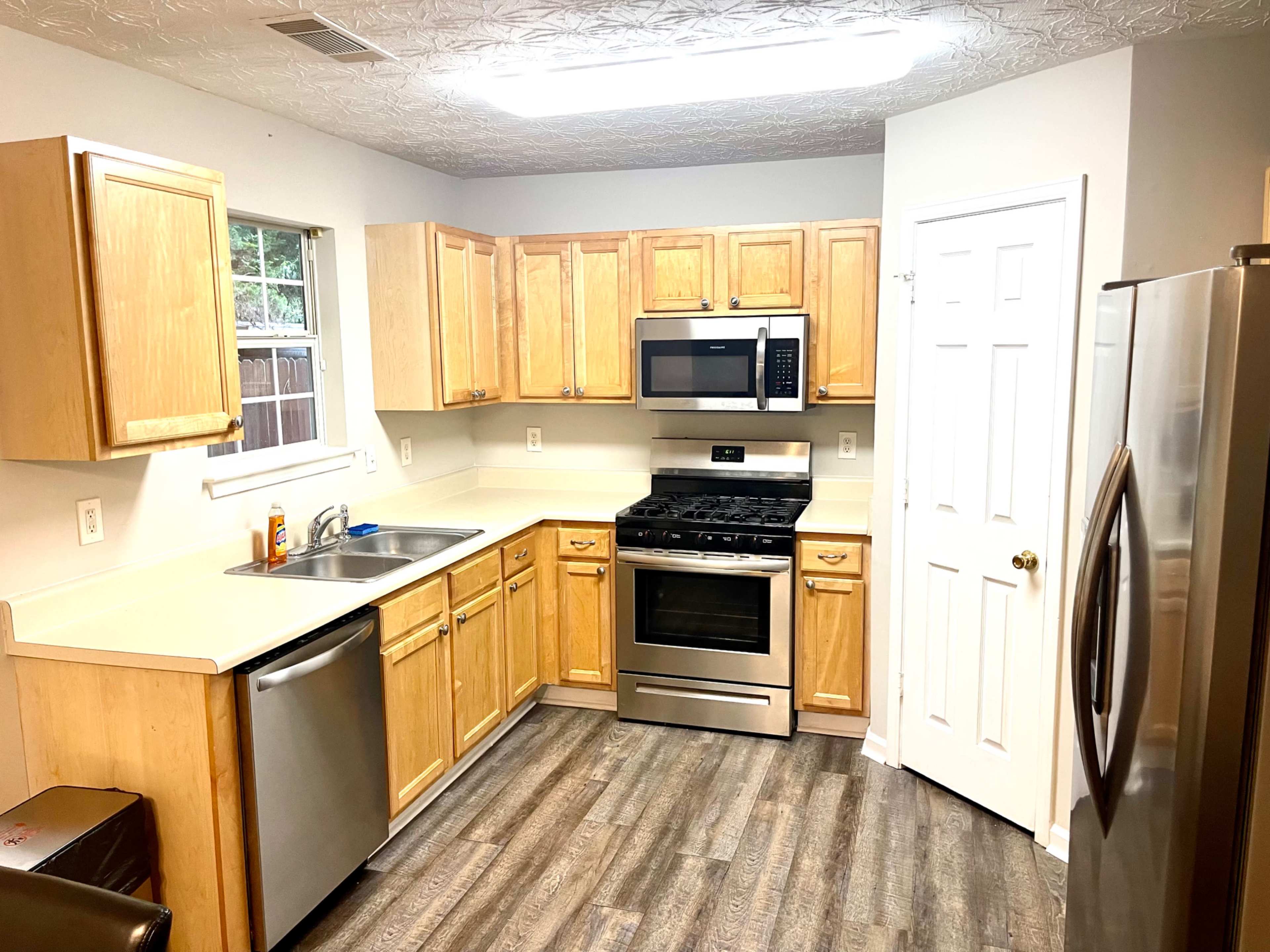 A kitchen with wooden cabinets, stainless steel appliances, and a light-colored countertop.