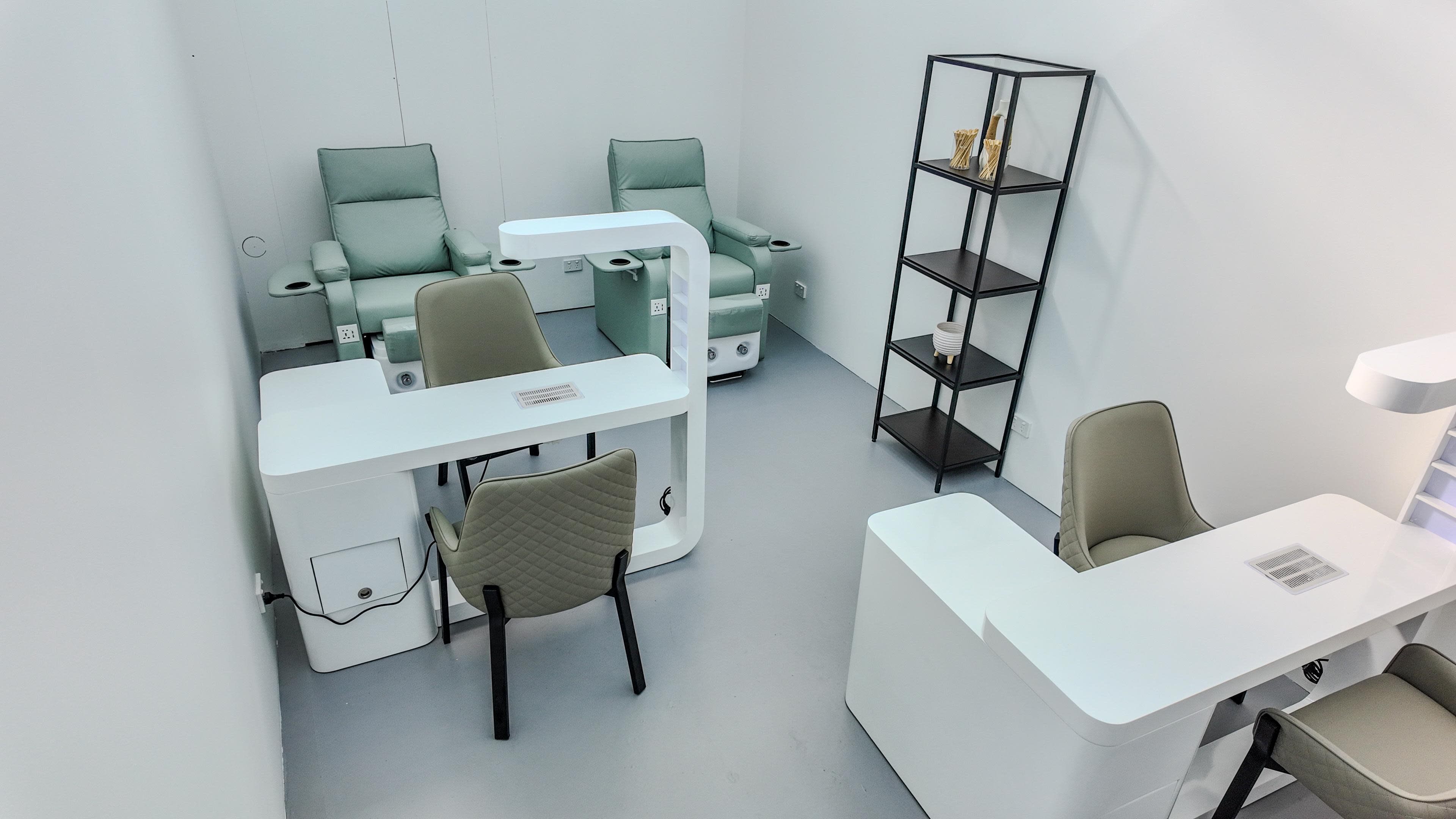 The image shows a minimalist salon interior with two green chairs, a black shelving unit, and two white workstations.