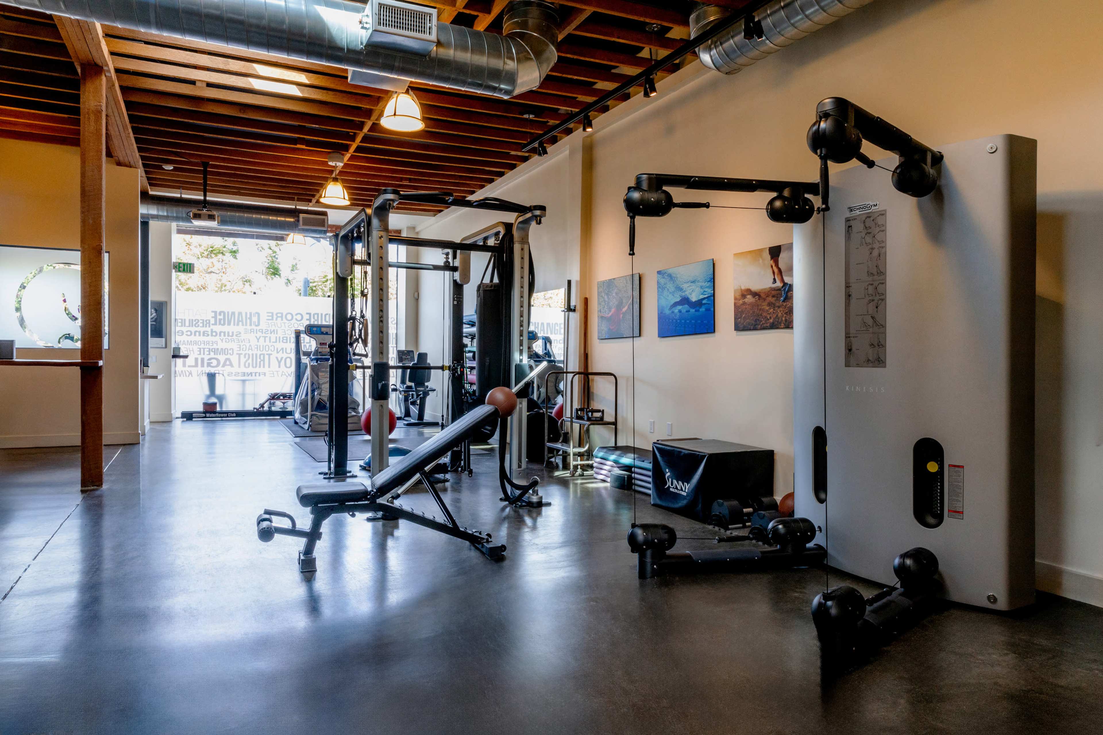 A well-equipped fitness gym with various exercise machines and weights arranged in a spacious, well-lit area.