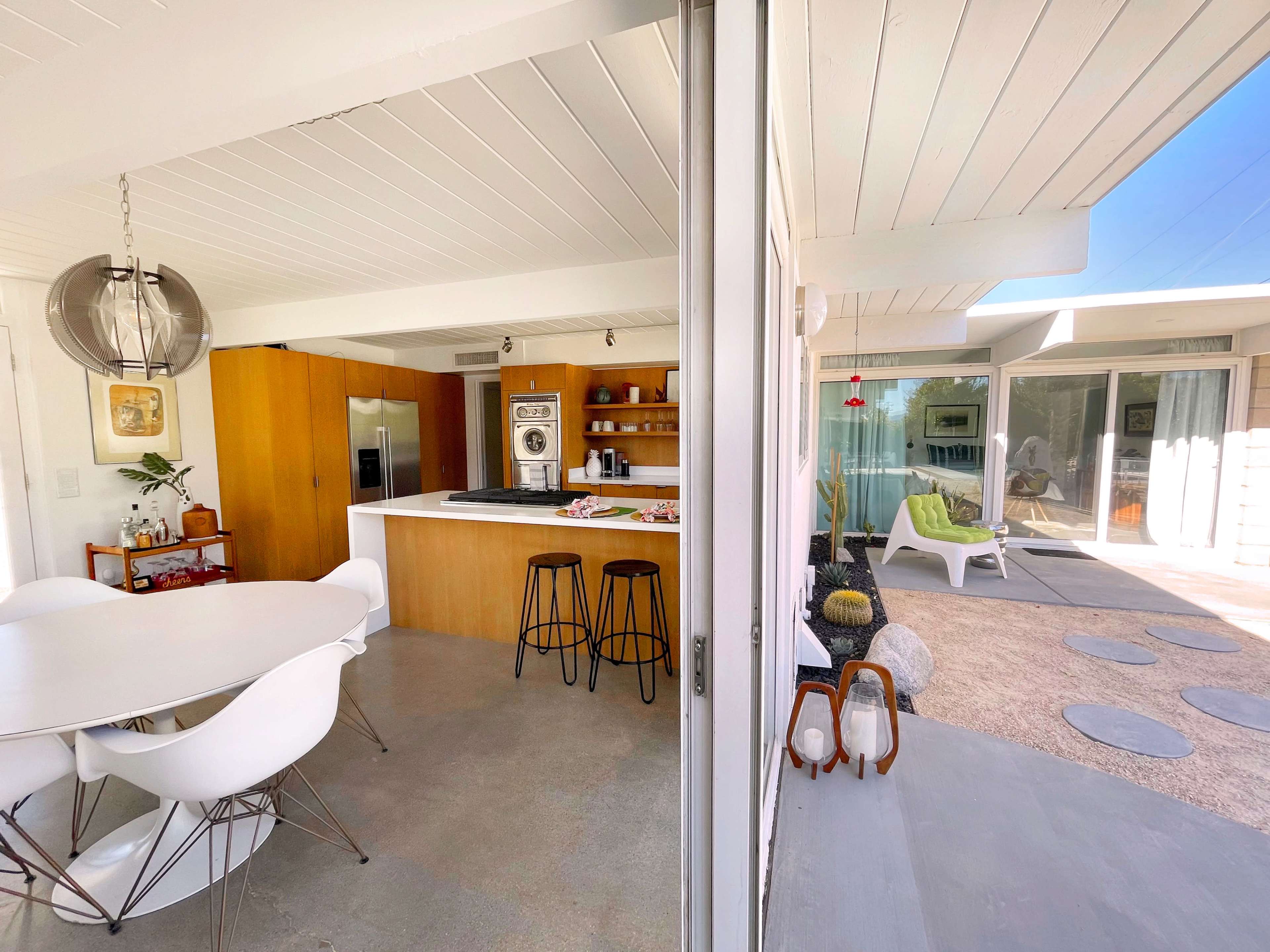 A modern open-concept living space with a kitchen, dining area, and seating outside enclosed by large glass doors.