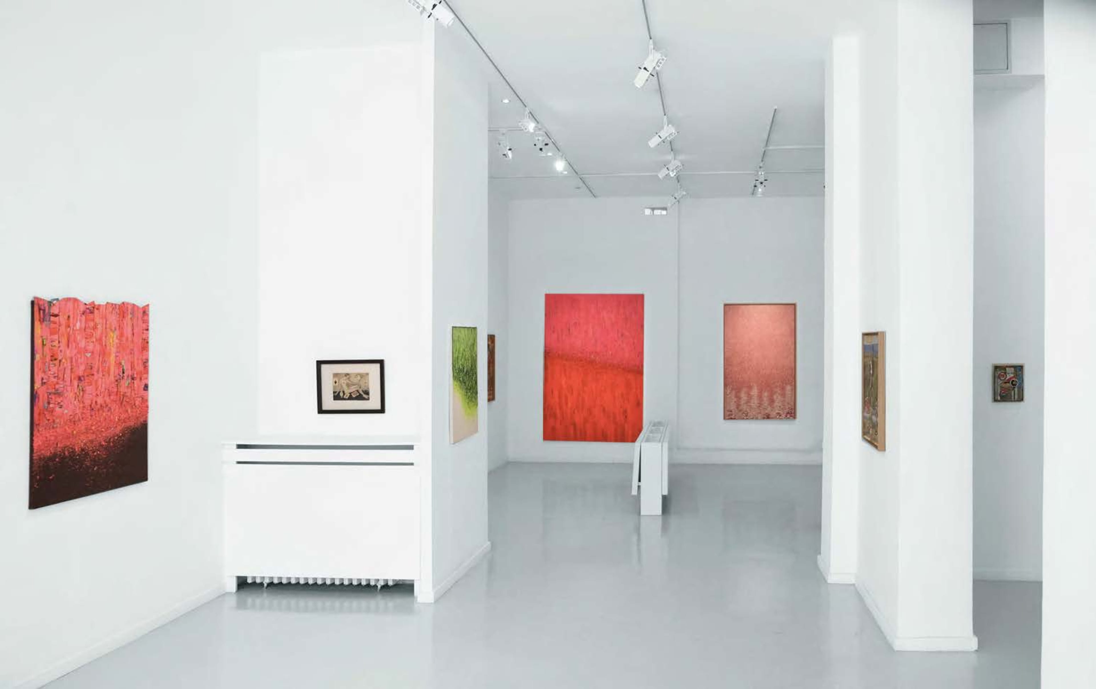 A spacious art gallery with white walls displaying various colorful paintings.