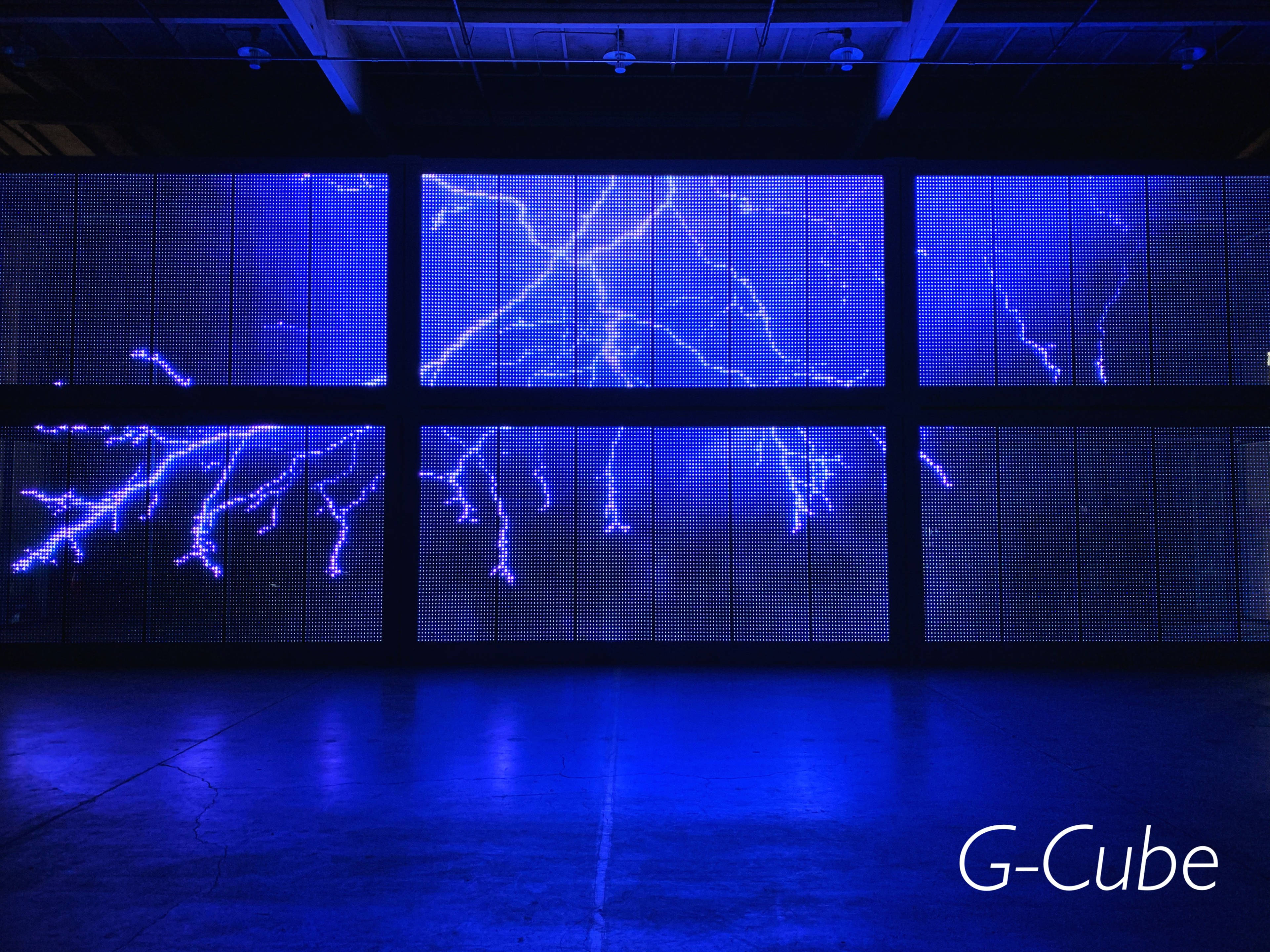 A large digital screen displaying a blue lightning pattern in a dimly lit indoor space.