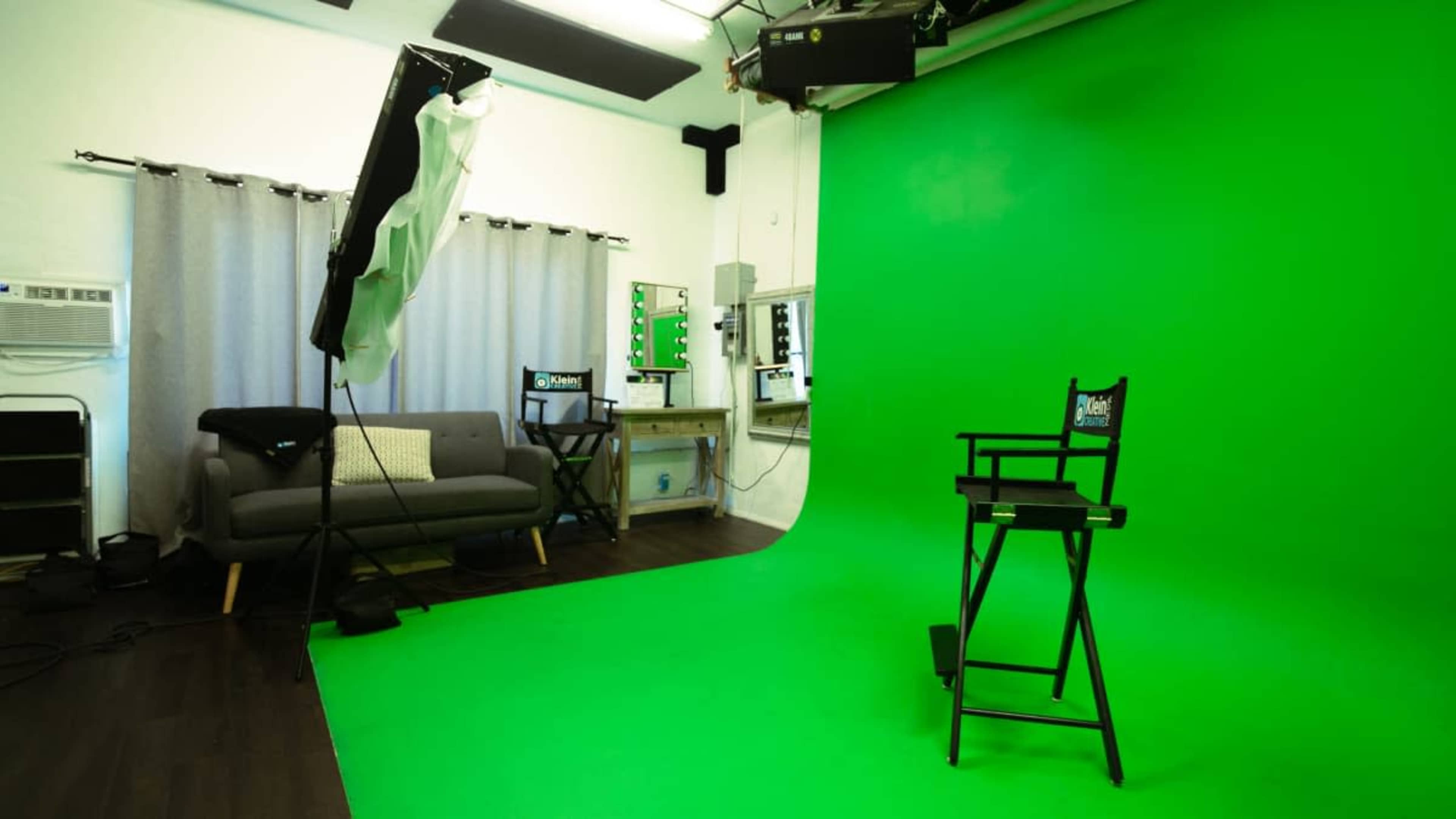The image shows a studio space with a bright green backdrop, a director's chair, soft lighting, and a sofa, along with mirrors and makeup stations.