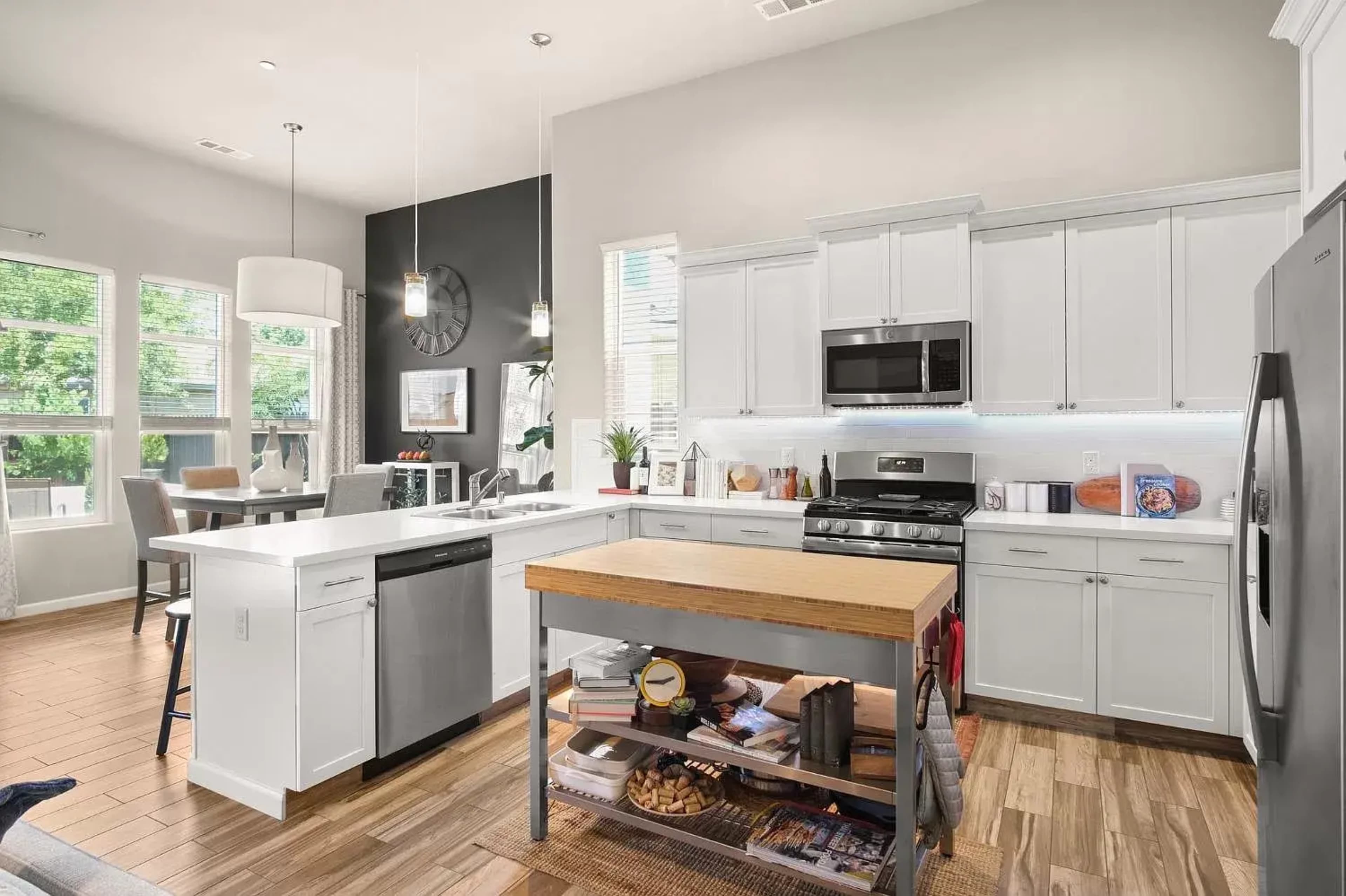 A modern kitchen with white cabinets, stainless steel appliances, and a wooden island in the center.