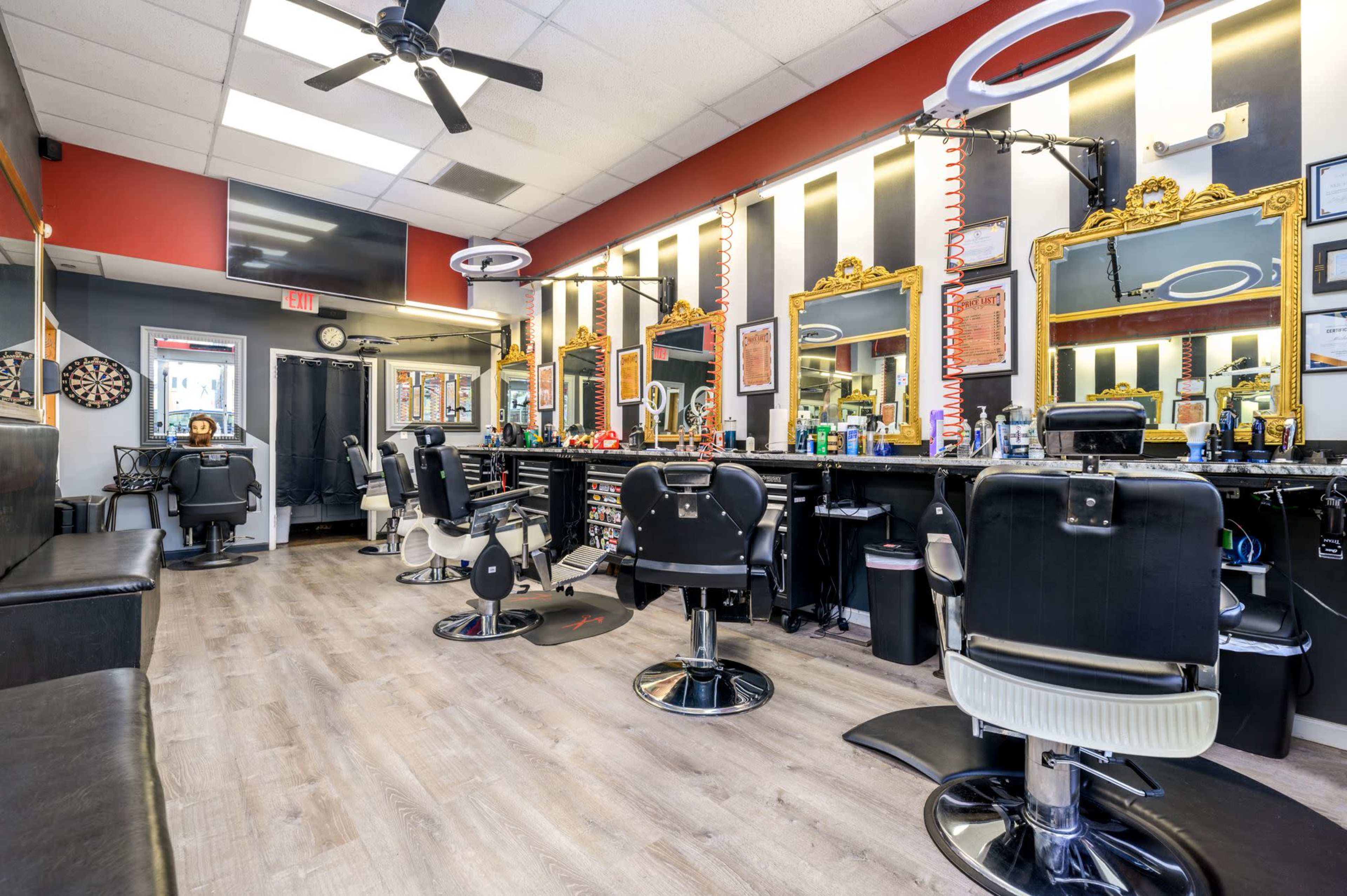A barber shop with several styling chairs, large mirrors, and a black and gold color scheme.
