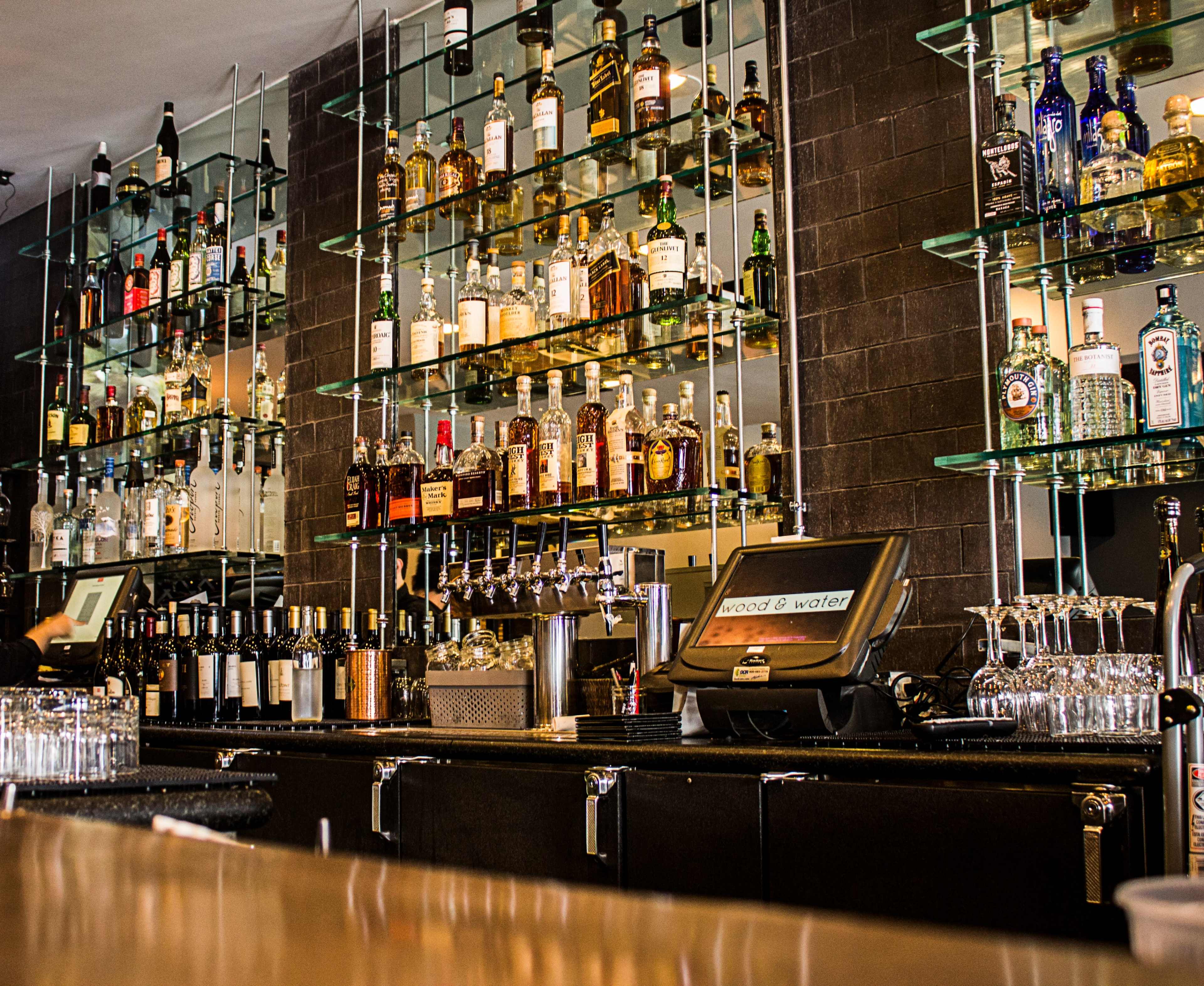 A well-stocked bar with shelves of various liquor bottles and a point-of-sale system on the counter.
