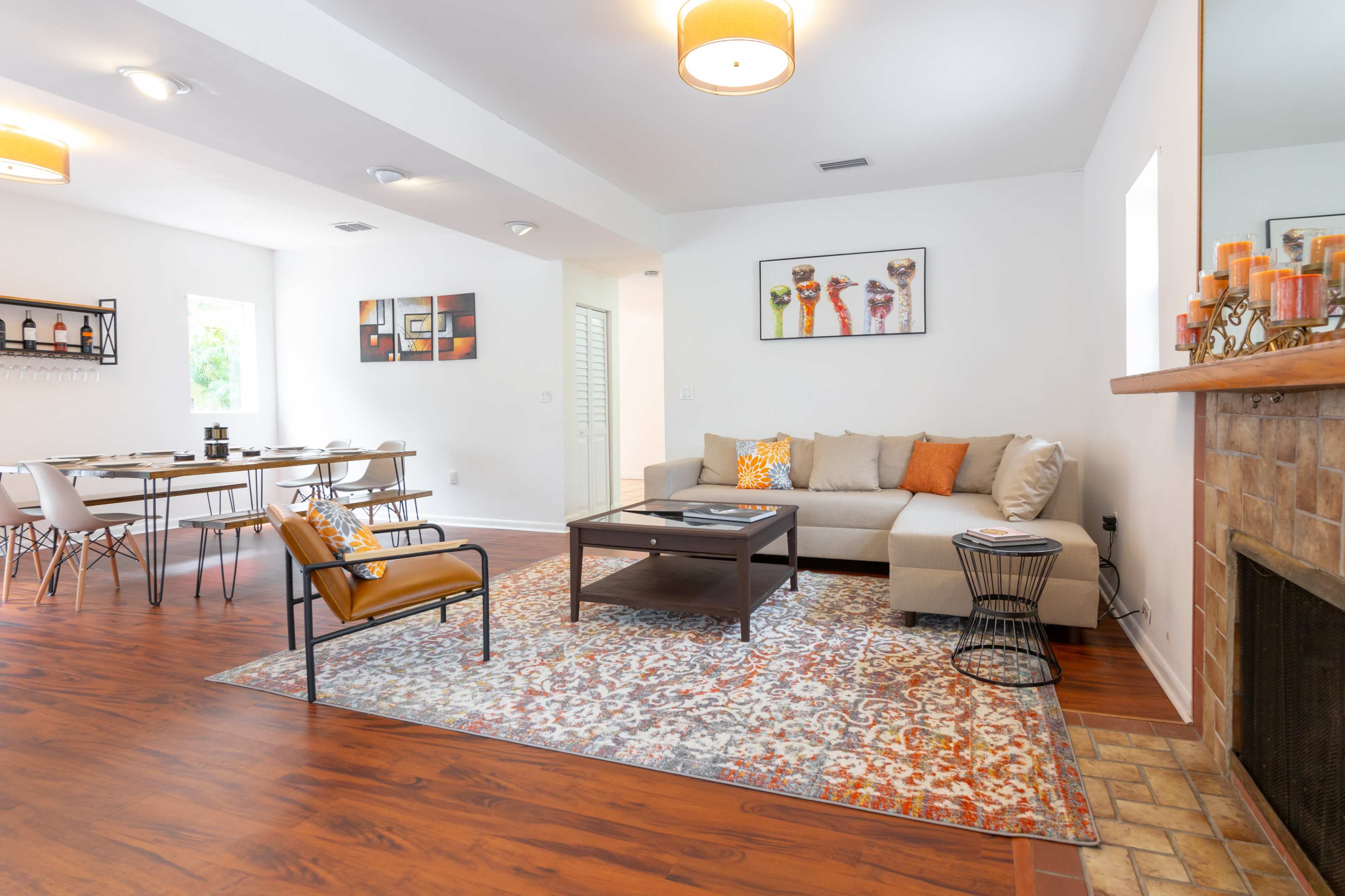 A modern living room with a couch, coffee table, and decorative rug, adjacent to a dining area with a table and chairs.