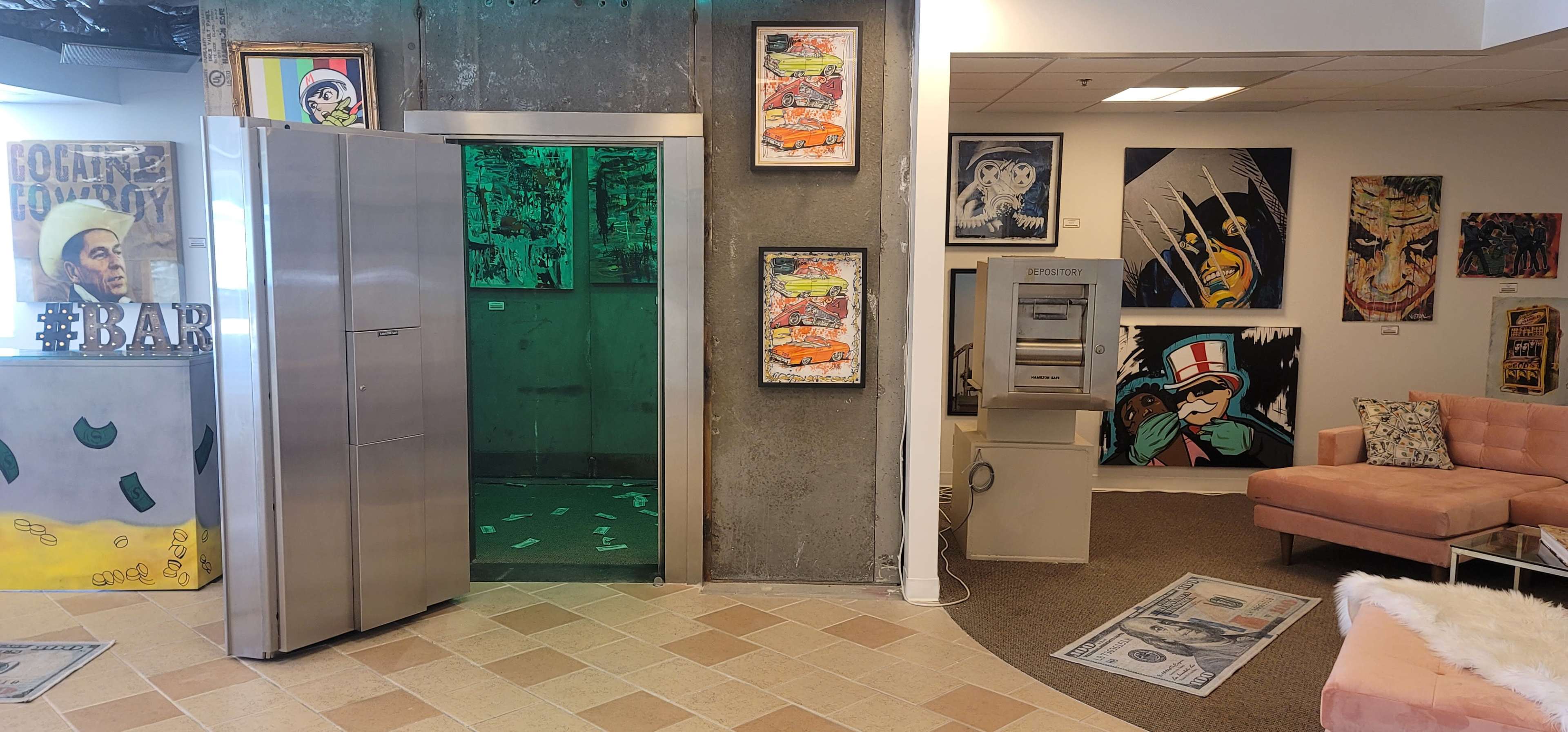 An interior space featuring a stainless steel refrigerator, an elevator with green lighting, a cash-themed rug, and various framed artworks on the walls, including pop art and comic-style pieces, alongside a pink couch and an ATM.