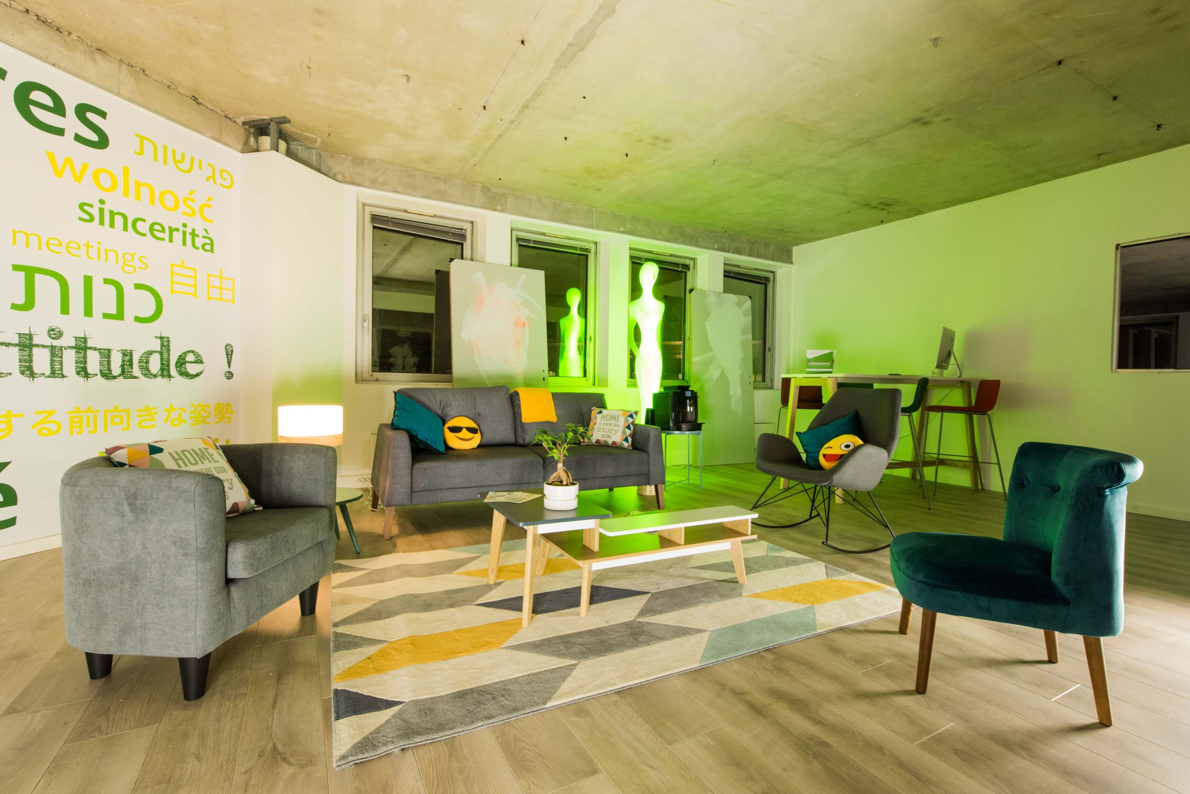A modern interior scene with a lounge area that includes a gray sofa, two accent chairs, a coffee table, and colorful wall art.