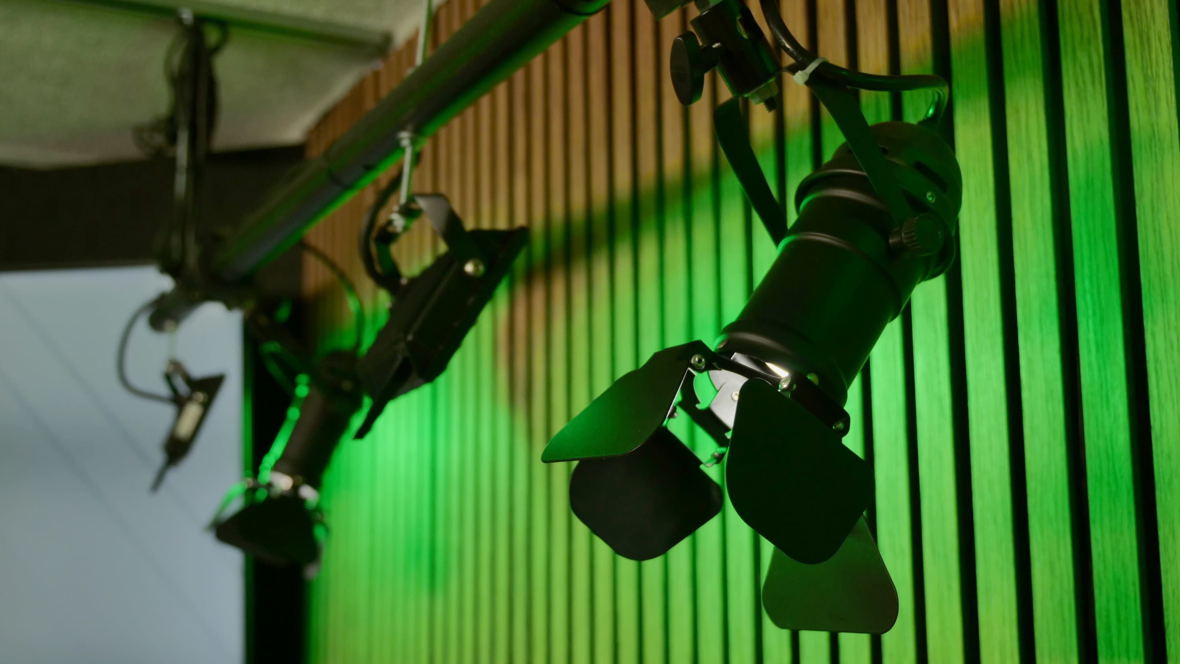 The image shows studio lighting fixtures mounted on a wooden wall, casting green light.