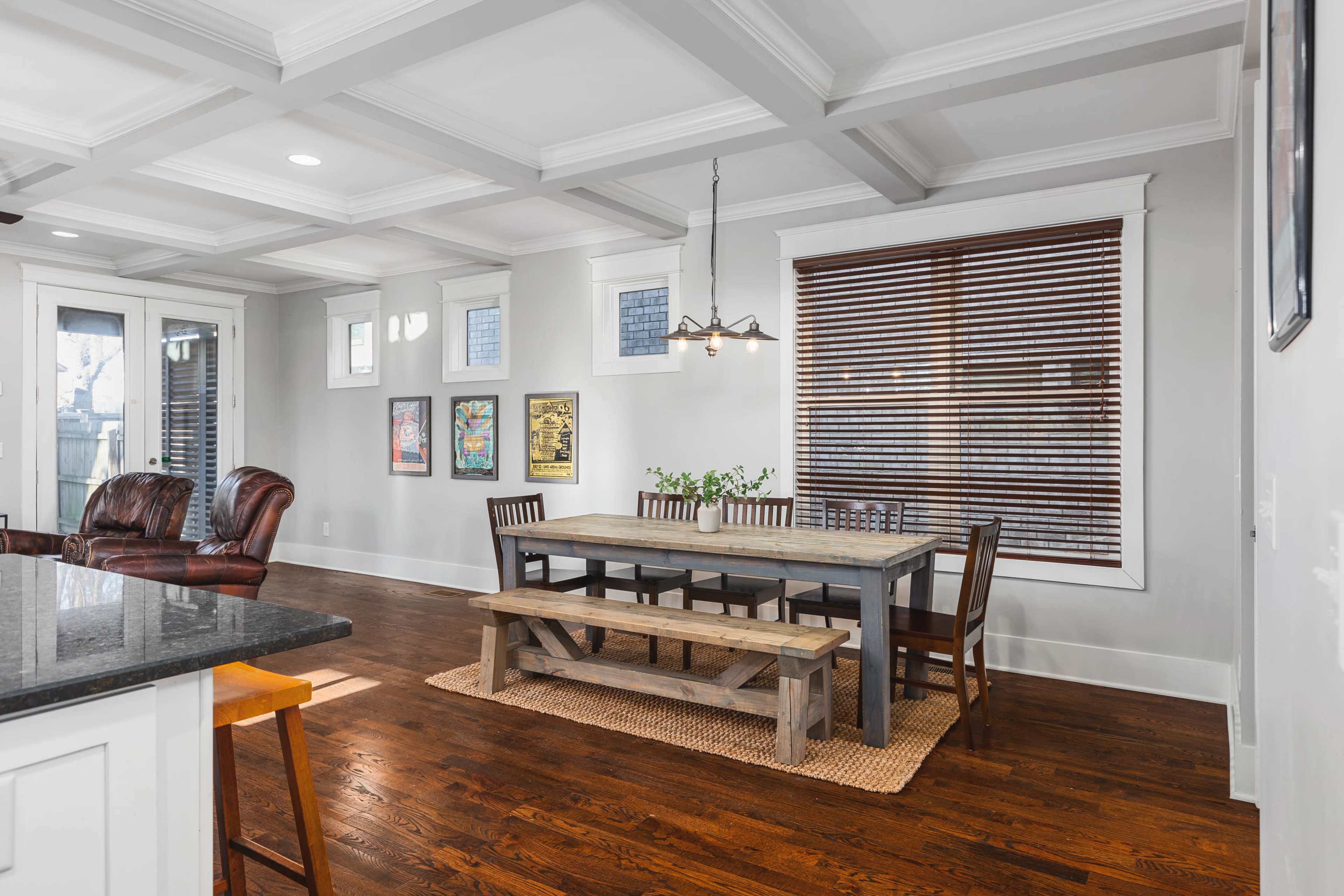 A spacious dining area with a large wooden table surrounded by chairs, complemented by a set of windows featuring wooden blinds.