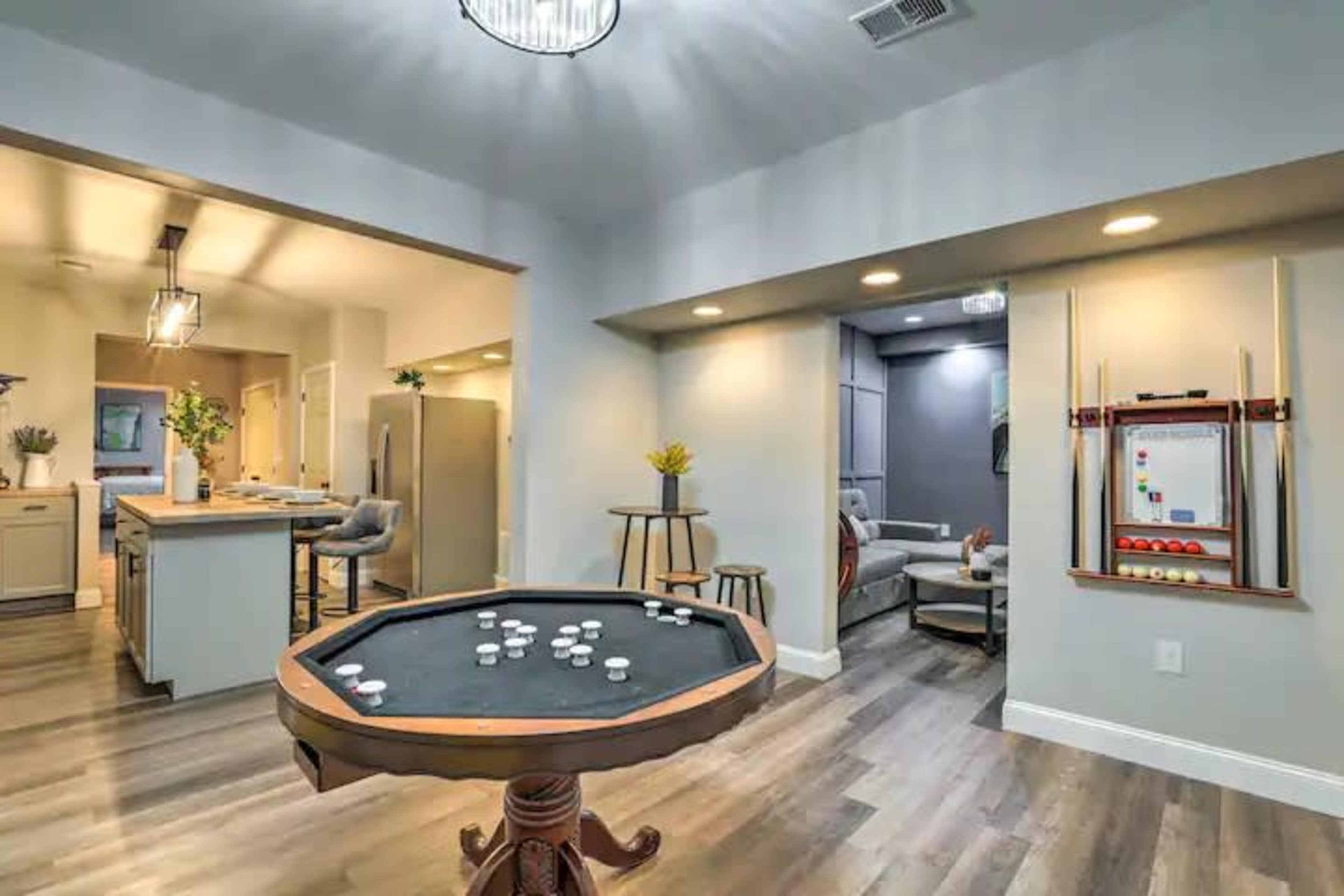 A modern game room featuring a pool table, with an open layout connecting to a kitchen and living area.