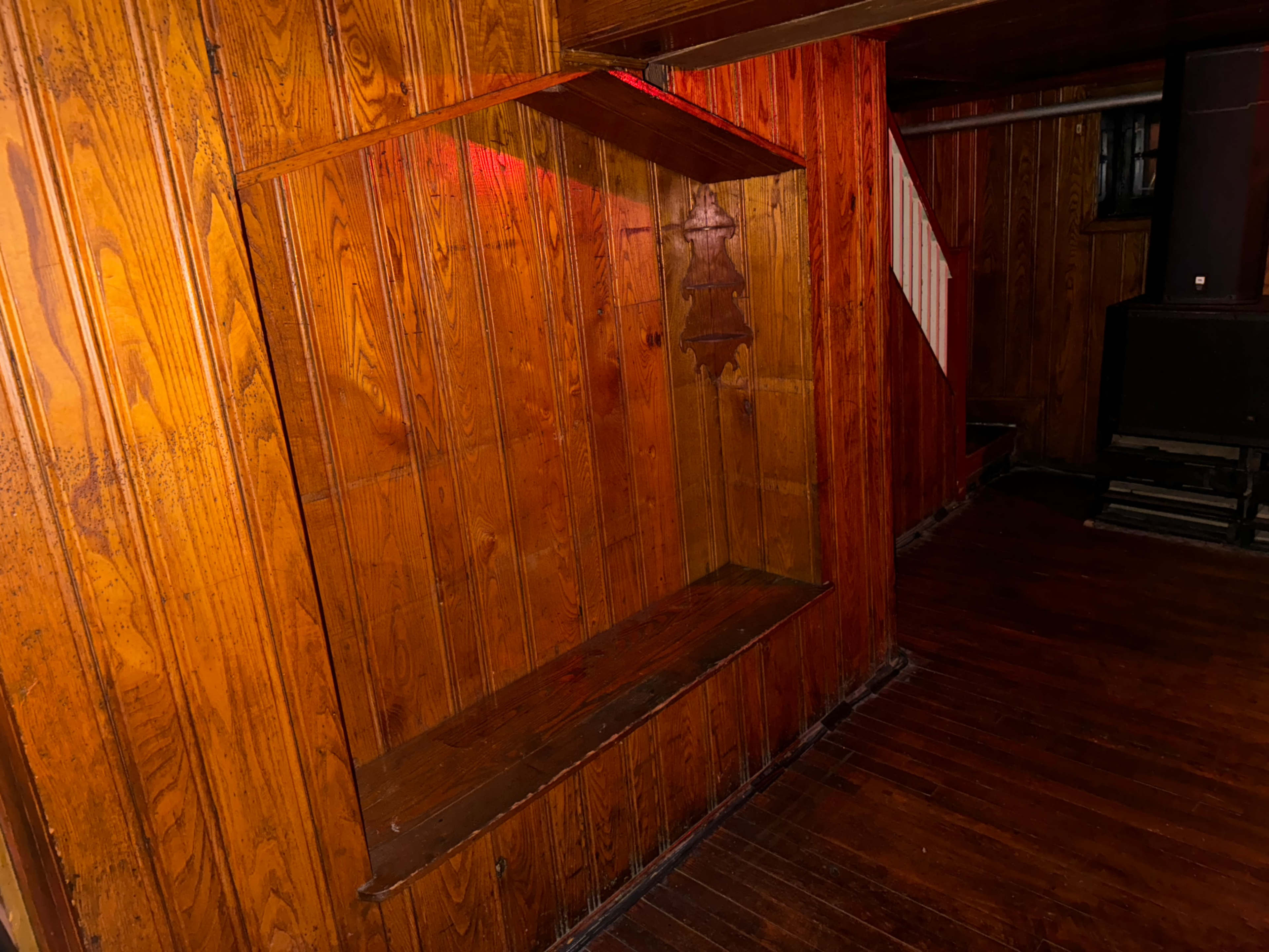 A wooden interior with dark paneling and a built-in shelf against the wall.