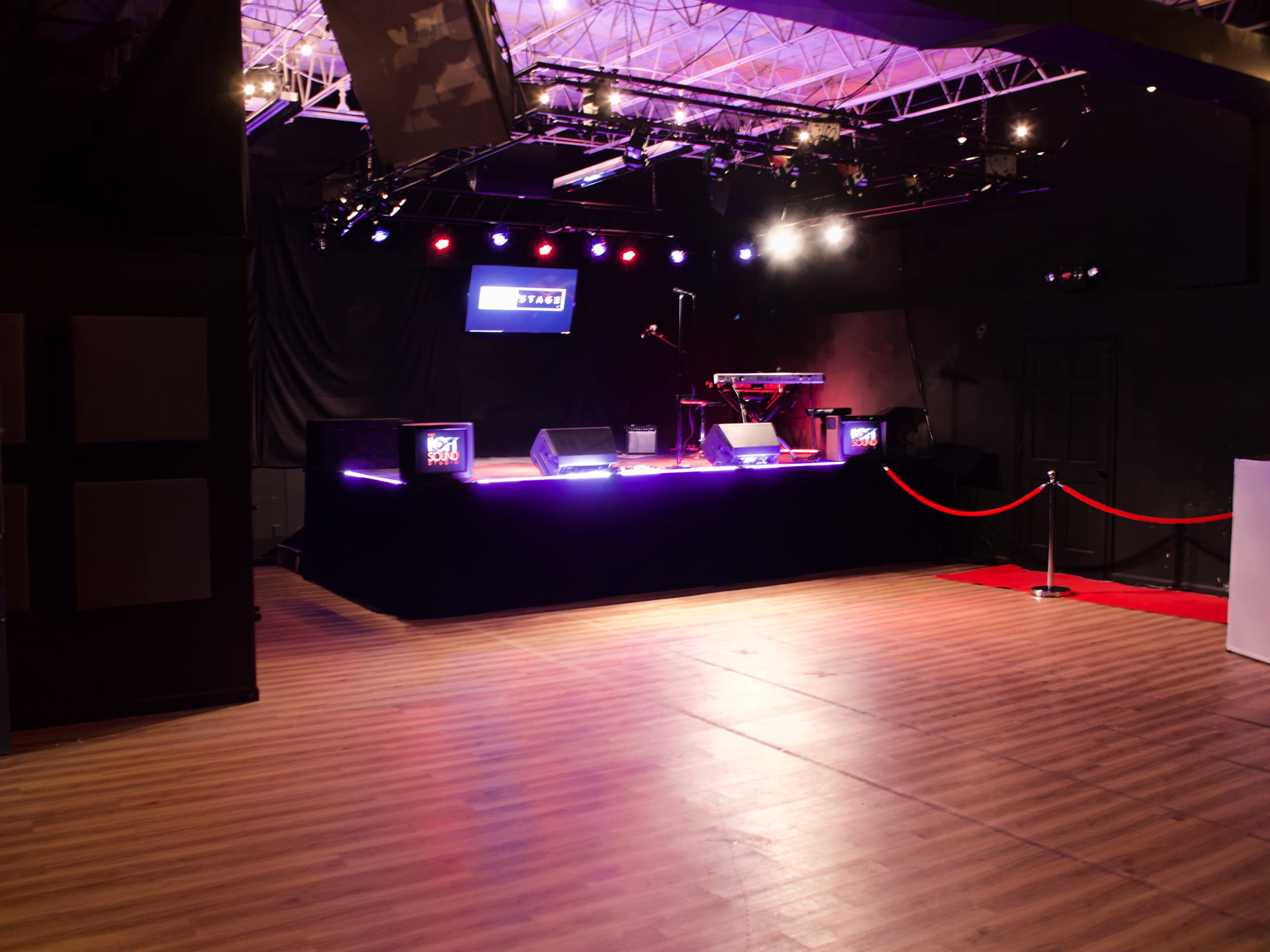 A stage with musical equipment, lighting, and red ropes in a well-lit performance venue.