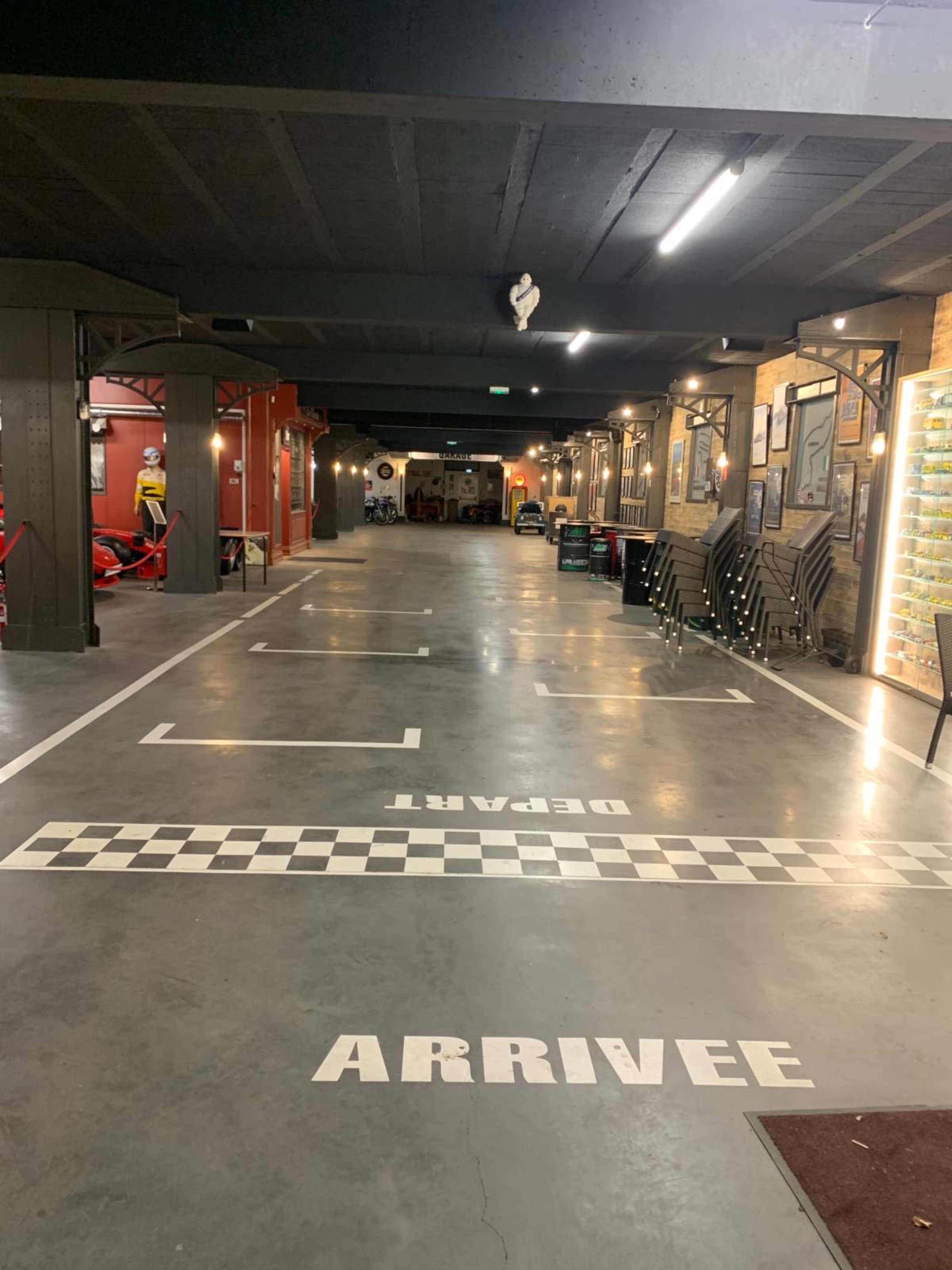 The image shows an interior parking area with marked spaces that include the words "ARRIVEE" and "DEPART", and a checkered line on the floor.