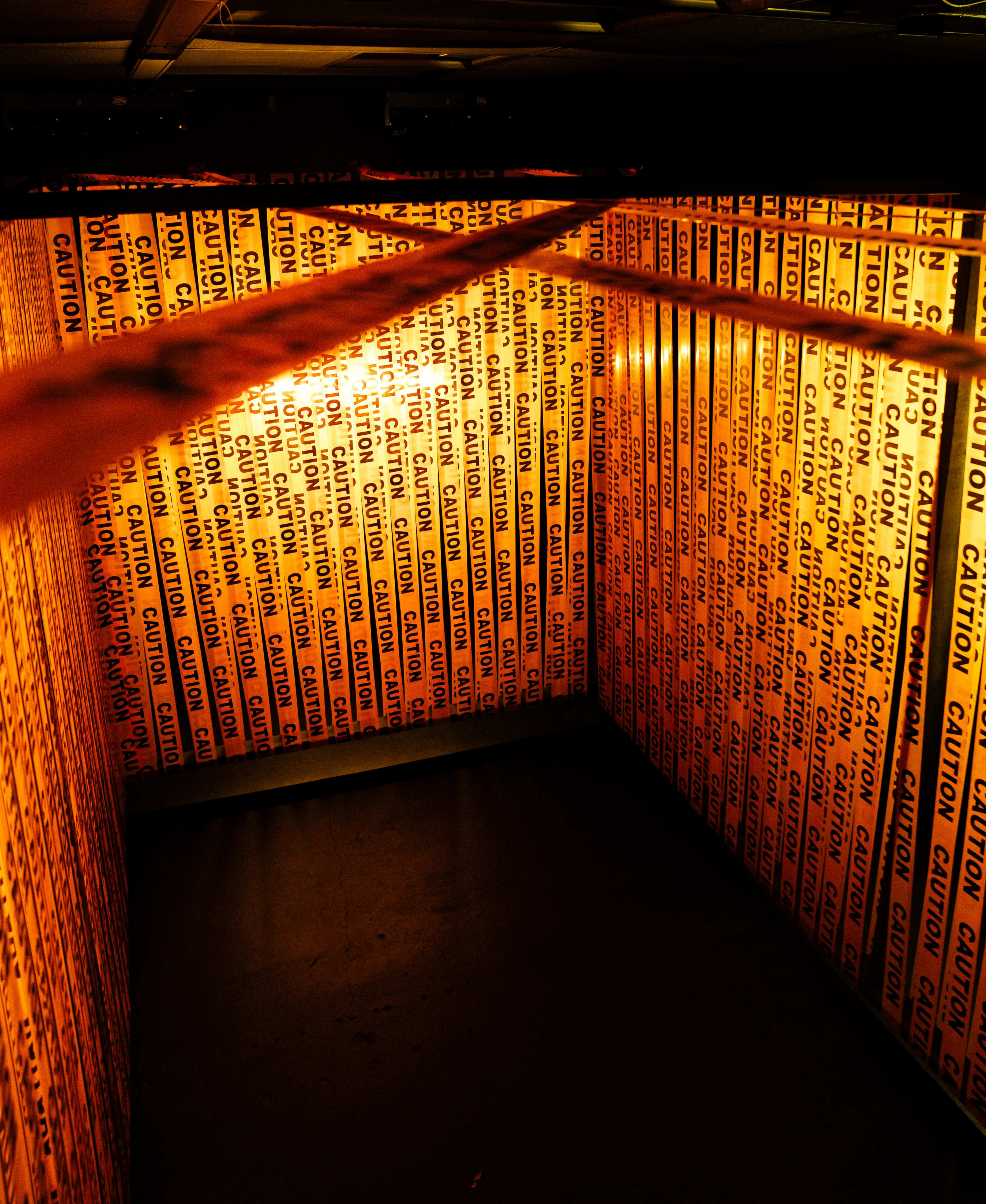The image shows a small, enclosed space lined with bright yellow caution tape from floor to ceiling.
