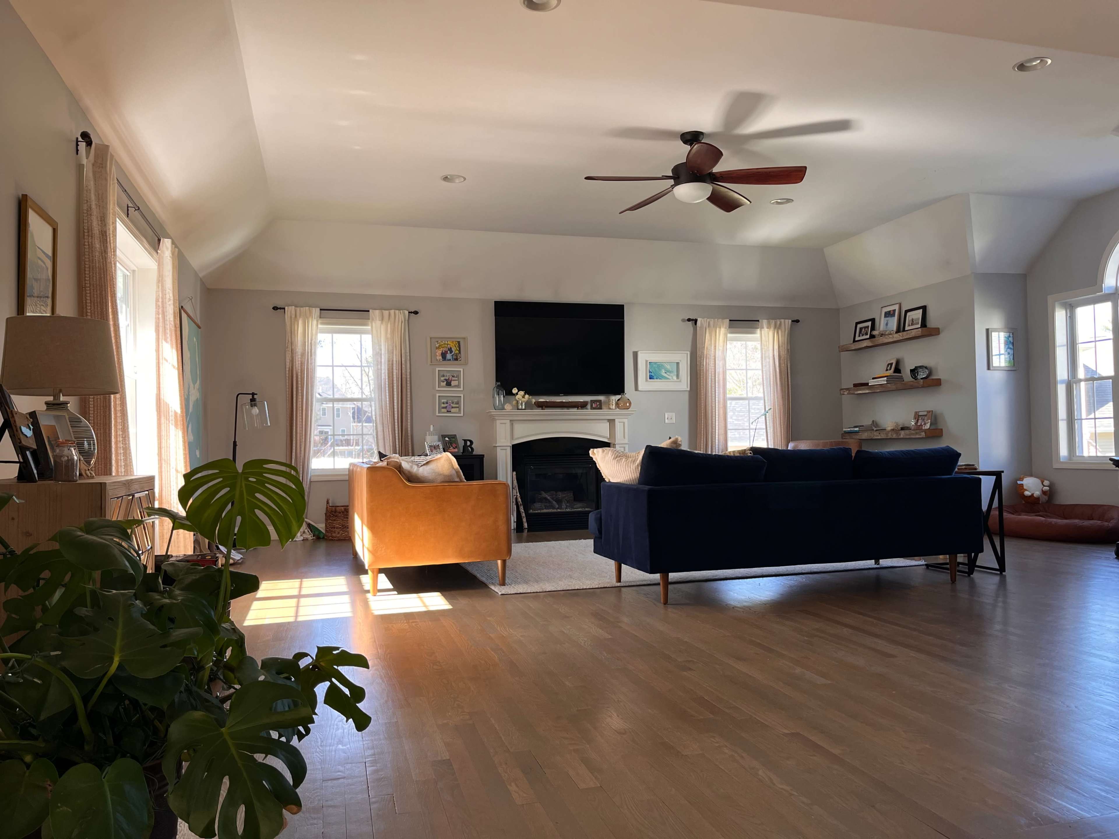 A spacious living room with a fireplace, two sofas, and large windows allowing natural light to enter.