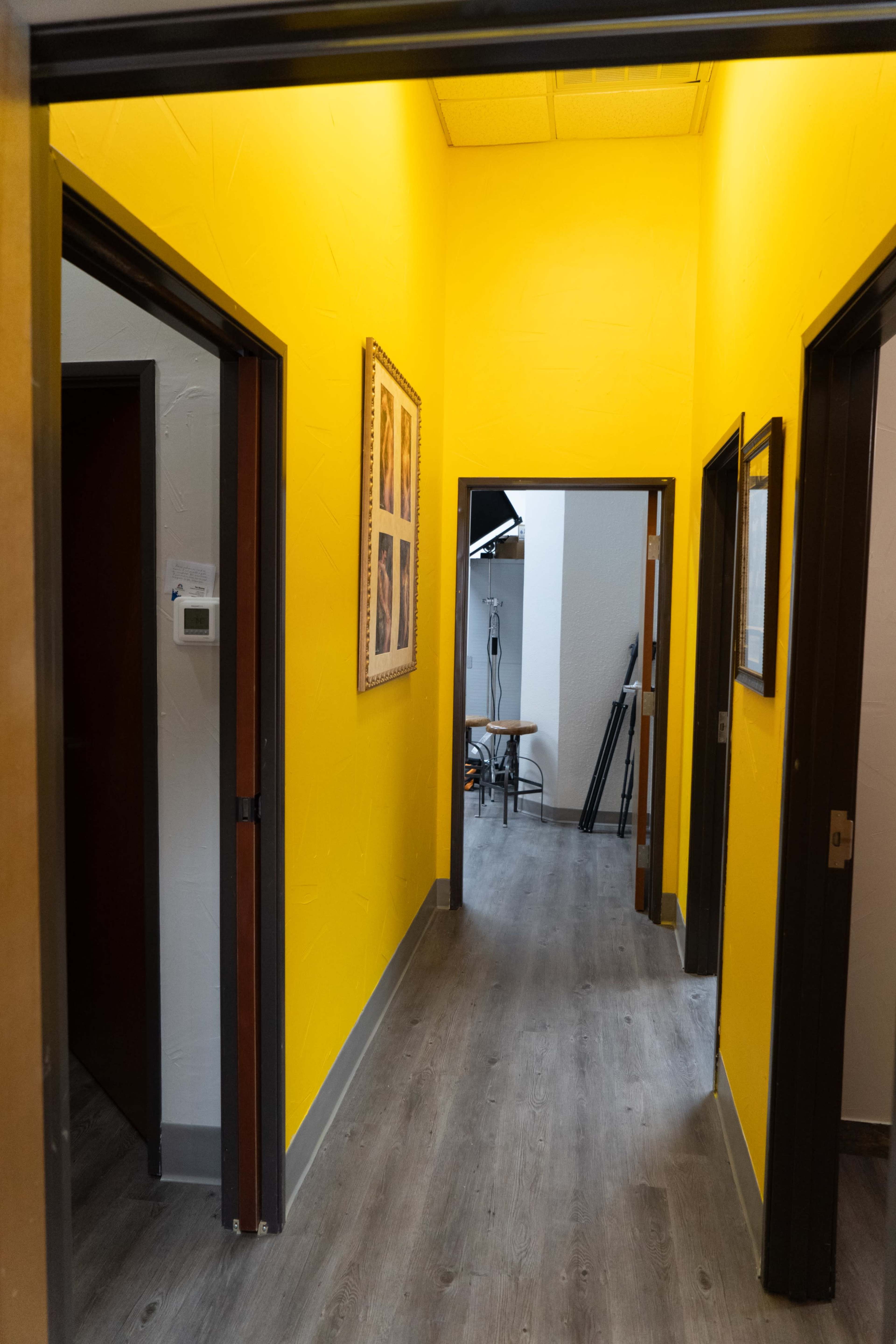 A narrow hallway with yellow walls and wooden doors on either side, leading to another room at the end.