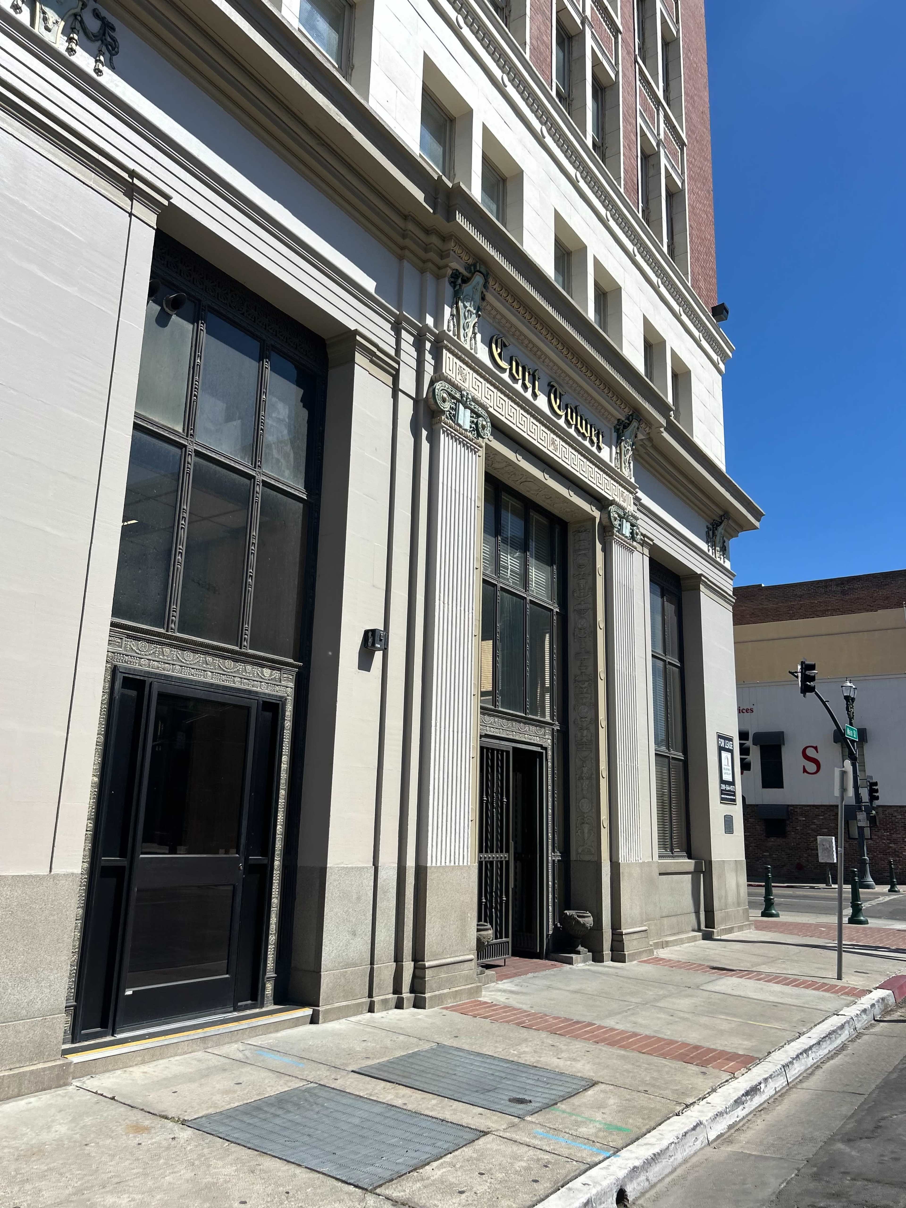 The image shows the entrance of a historic courthouse building with intricate architectural details and large glass doors.