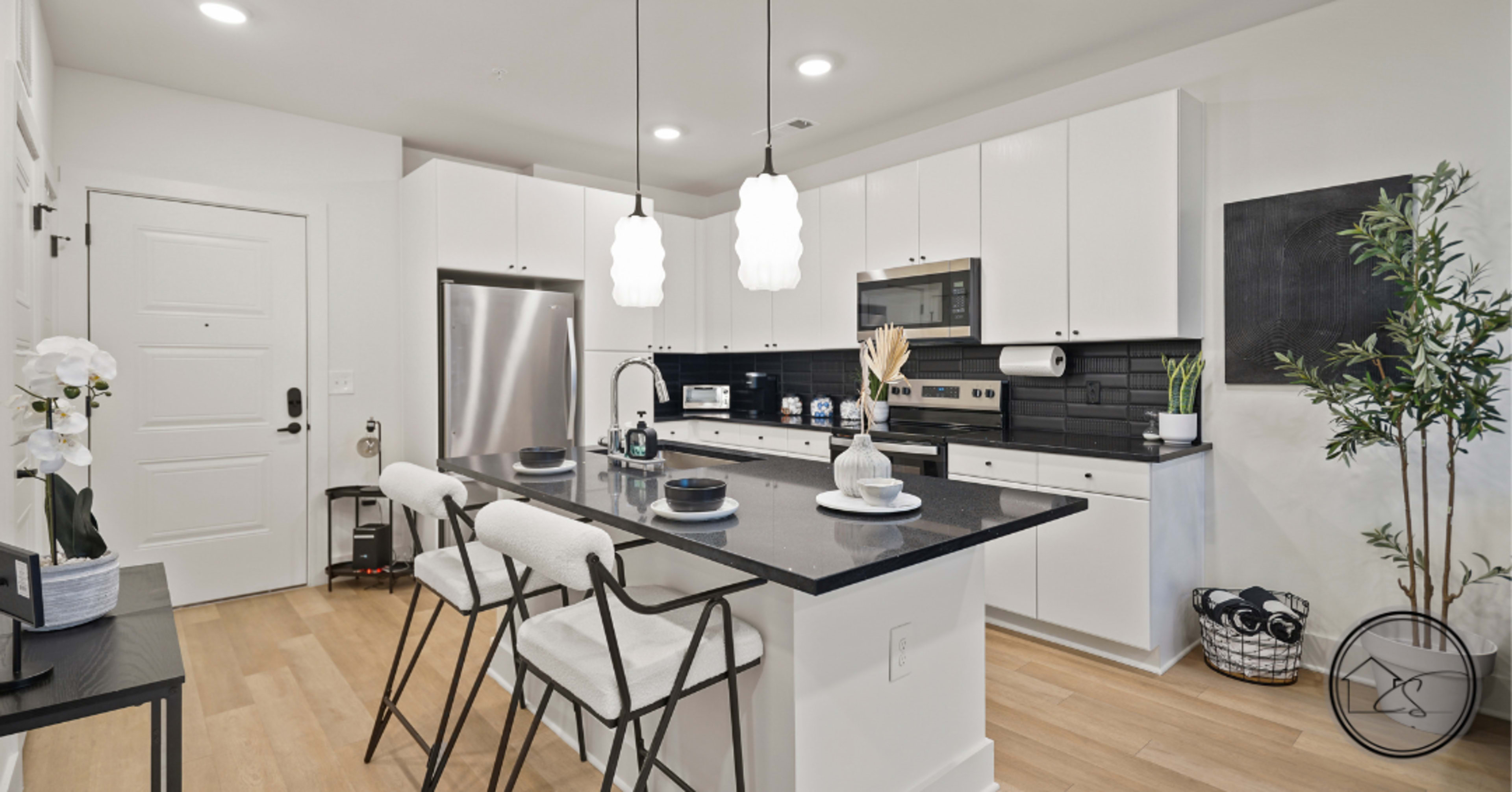 The kitchen features modern white cabinetry, stainless steel appliances, and a central island with seating.