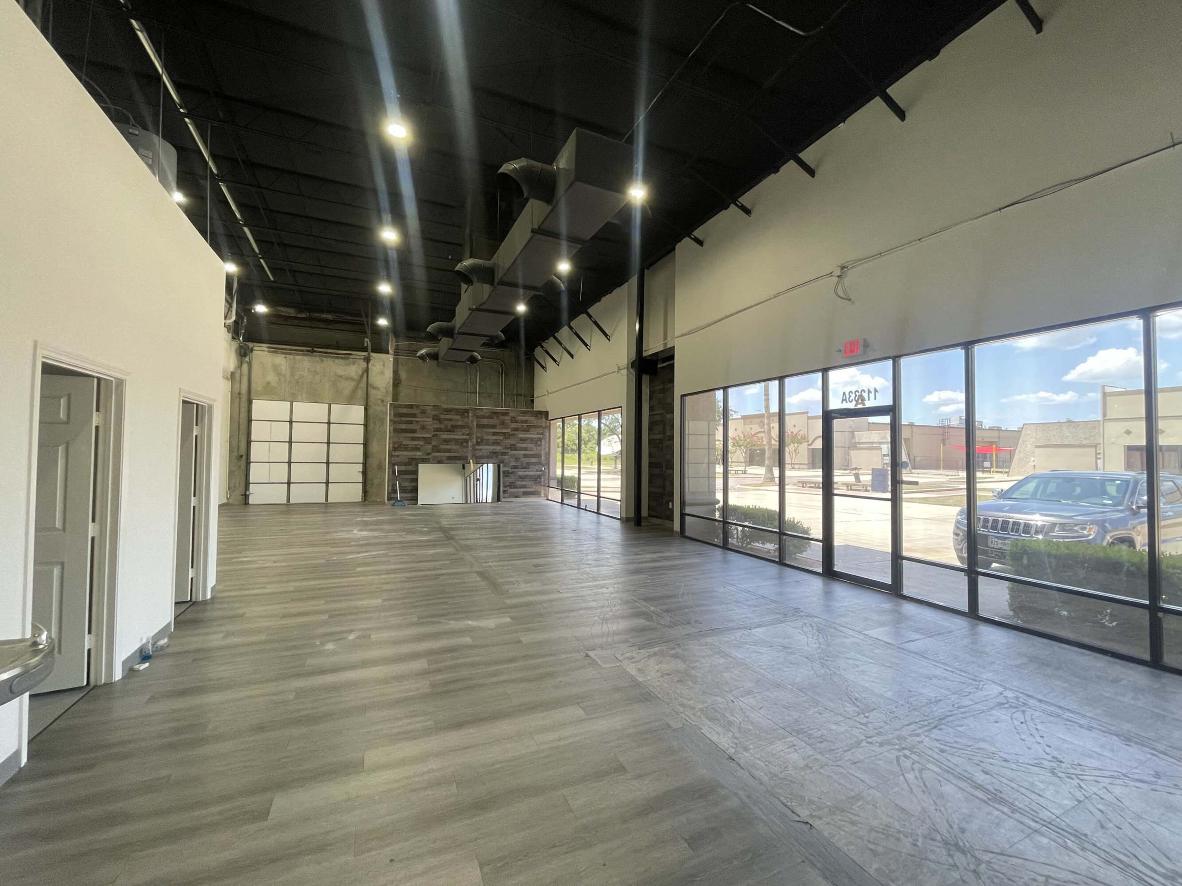A spacious, empty commercial interior with large windows and a polished wooden floor.
