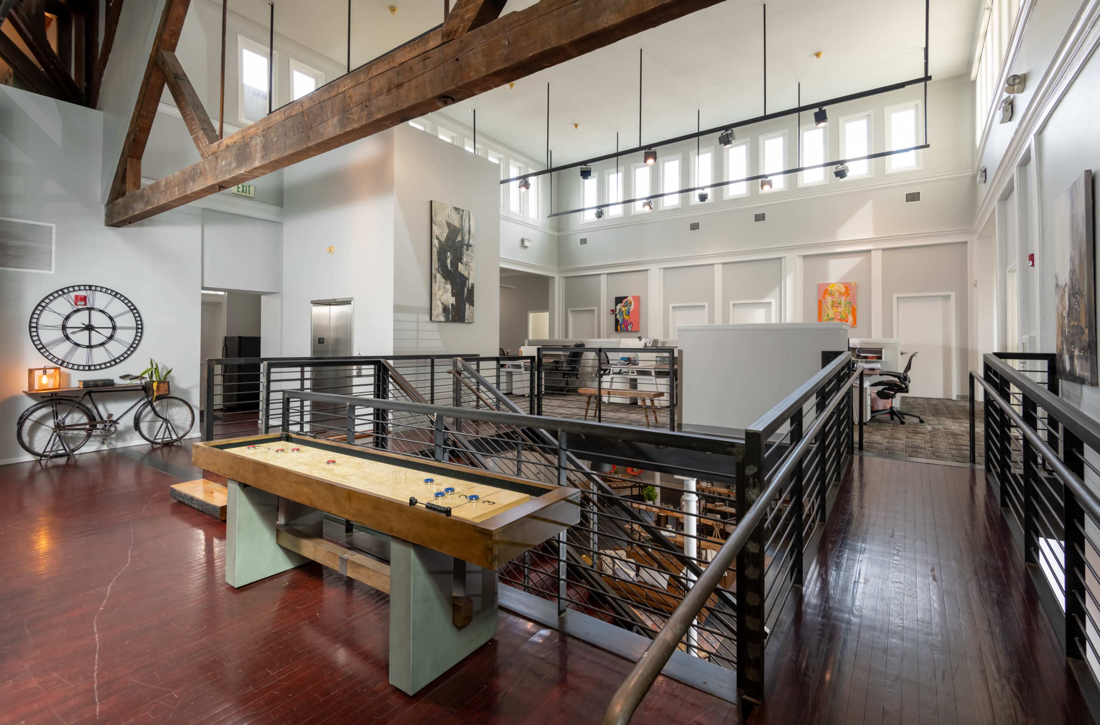 A spacious interior with high ceilings, featuring a wooden beam, modern furniture, and art on the walls.
