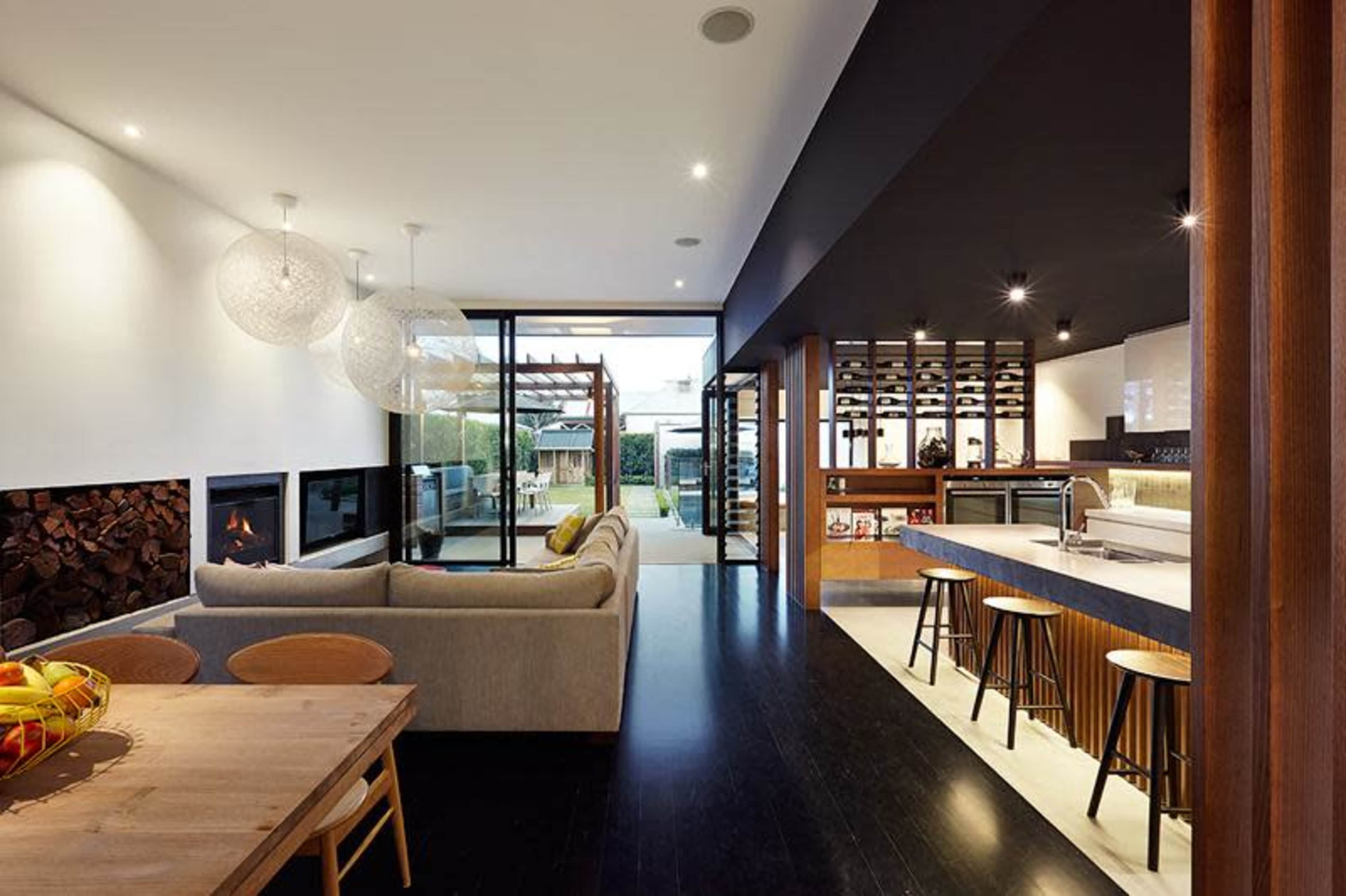 A modern open-concept living area with a sofa, dining table, and kitchen, showcasing large glass doors that lead to an outdoor space.