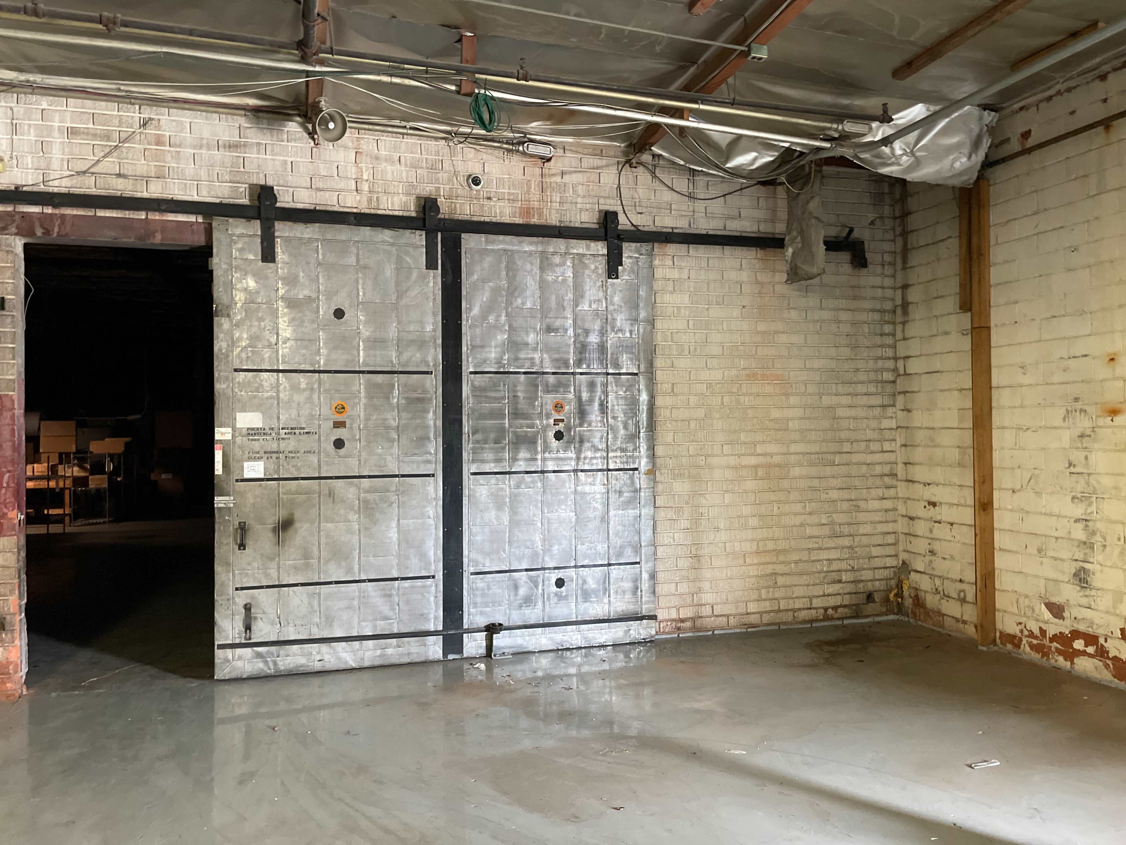A large, industrial metal door within a concrete-walled warehouse space.