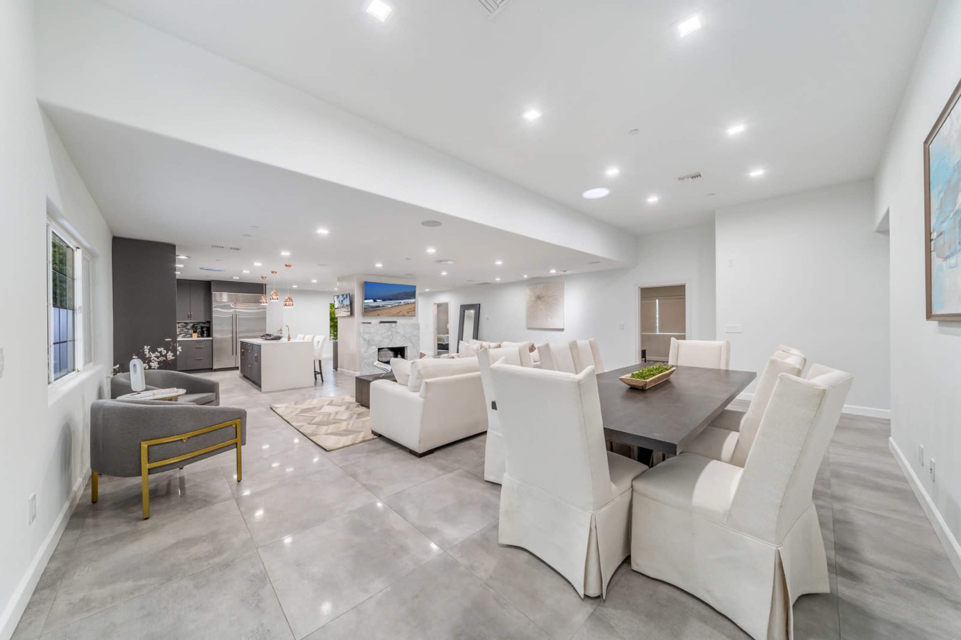 The image shows a modern, open-concept living and dining area with a large dining table and stylish seating arrangements.