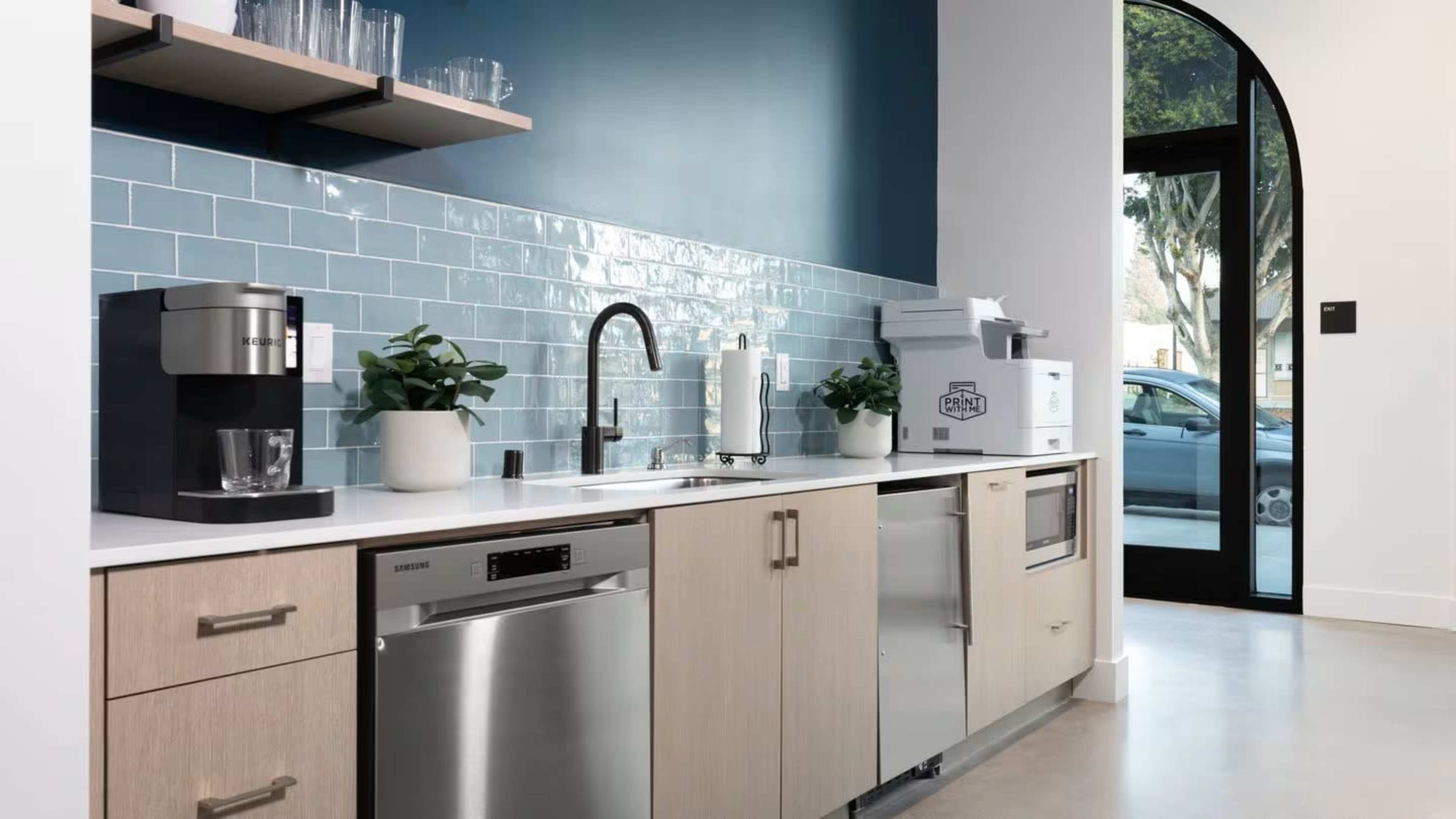 The modern kitchen features wooden cabinets, stainless steel appliances, and a blue tiled backsplash.