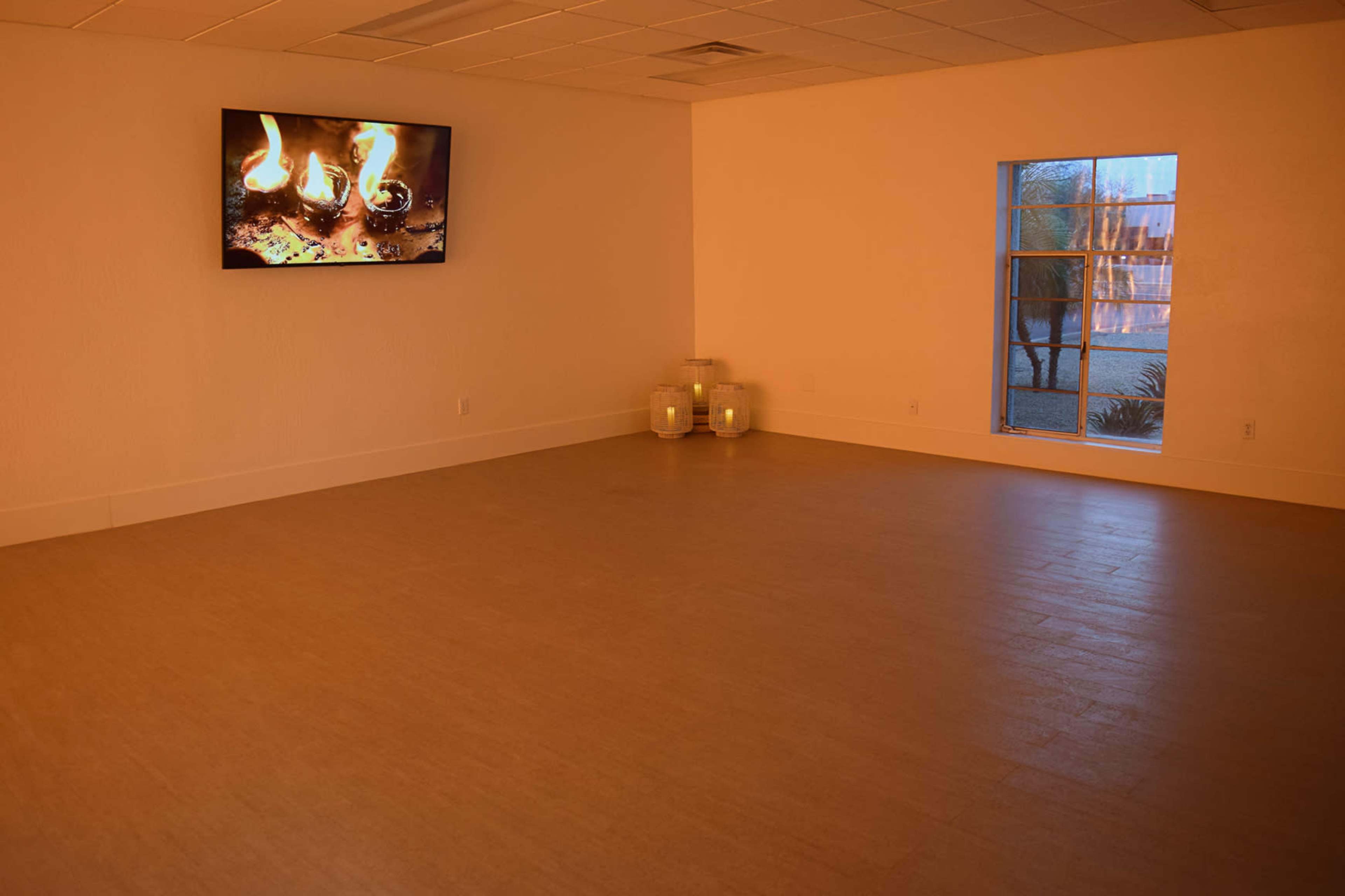 The room features a large television displaying flames, with a window and decorative jars in the corner.