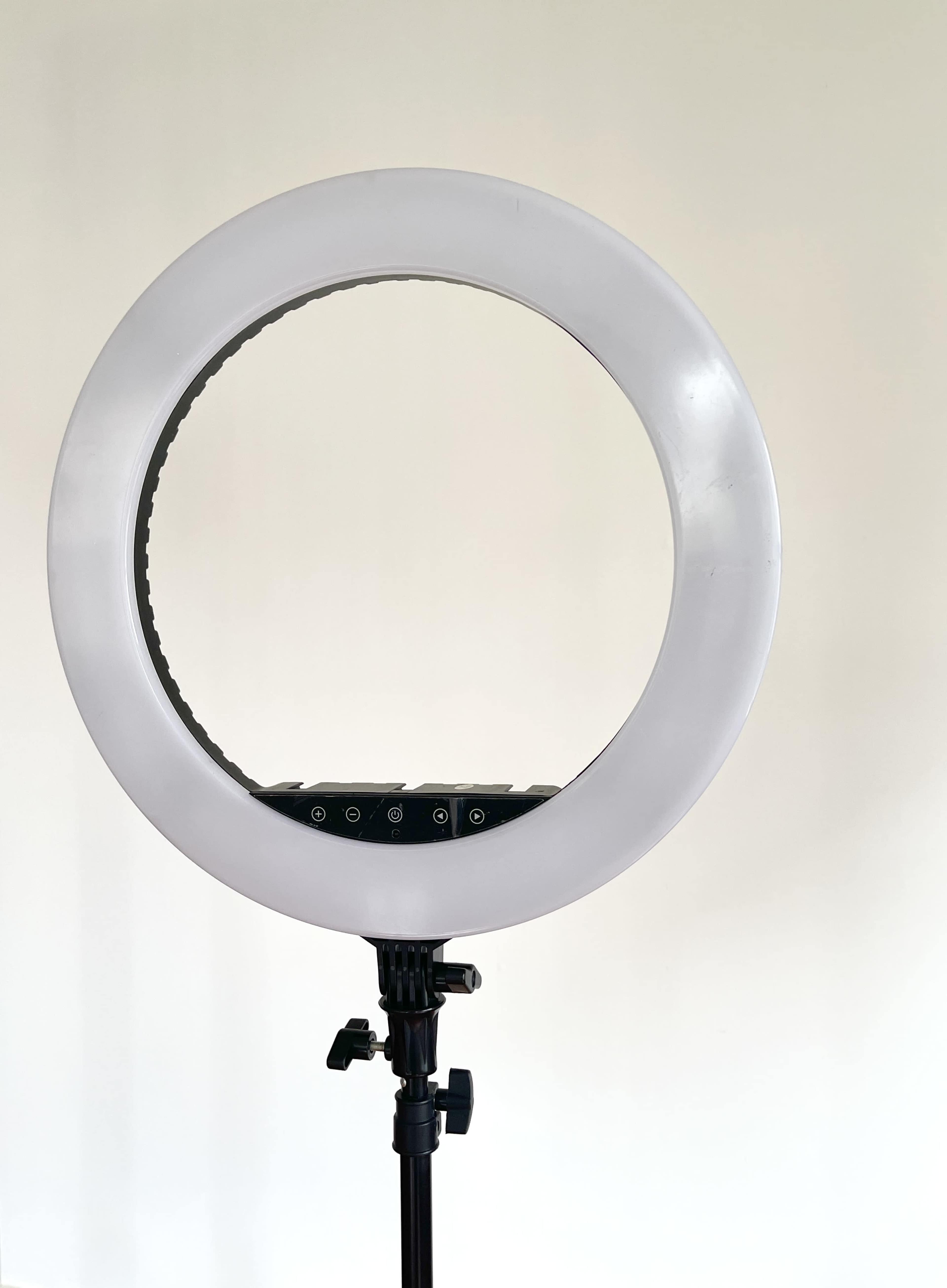A circular LED ring light is mounted on a black stand against a plain white background.