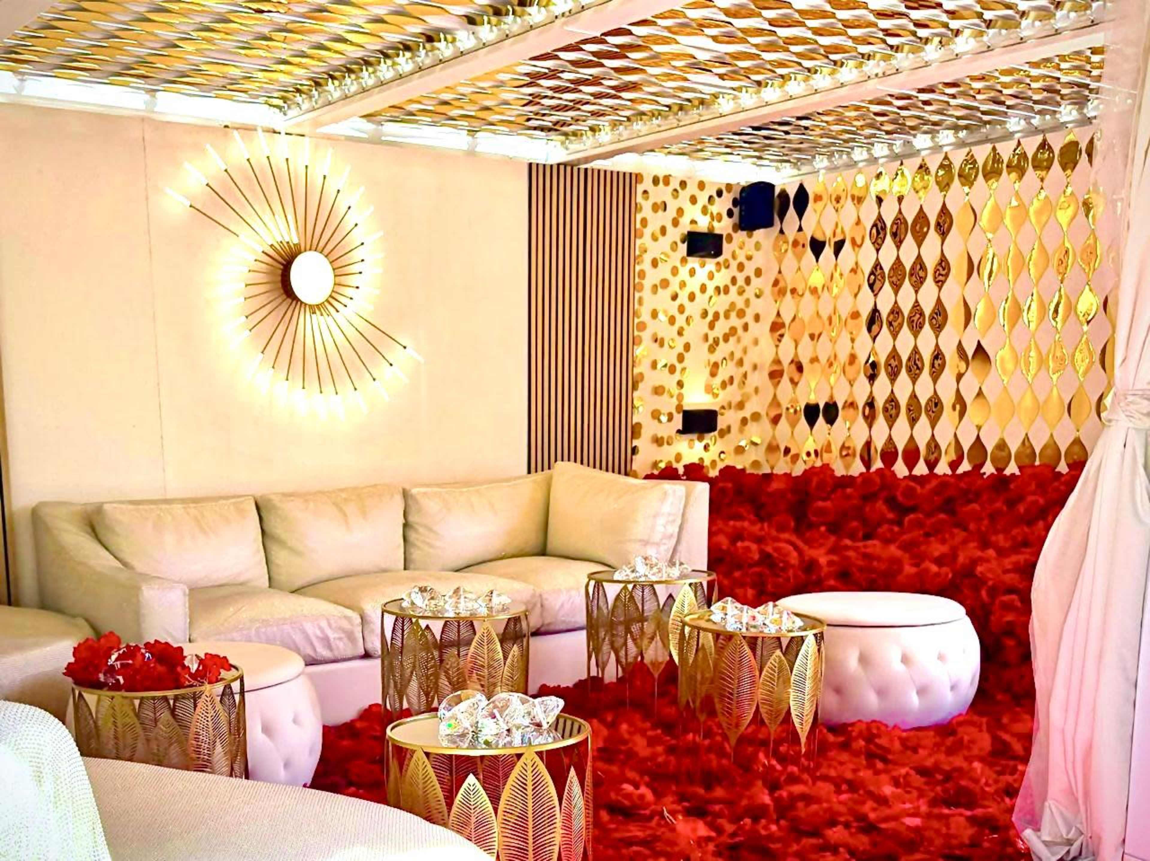 The scene features a luxurious lounge with white upholstered seating, golden decorative accents, and a vibrant red carpet.